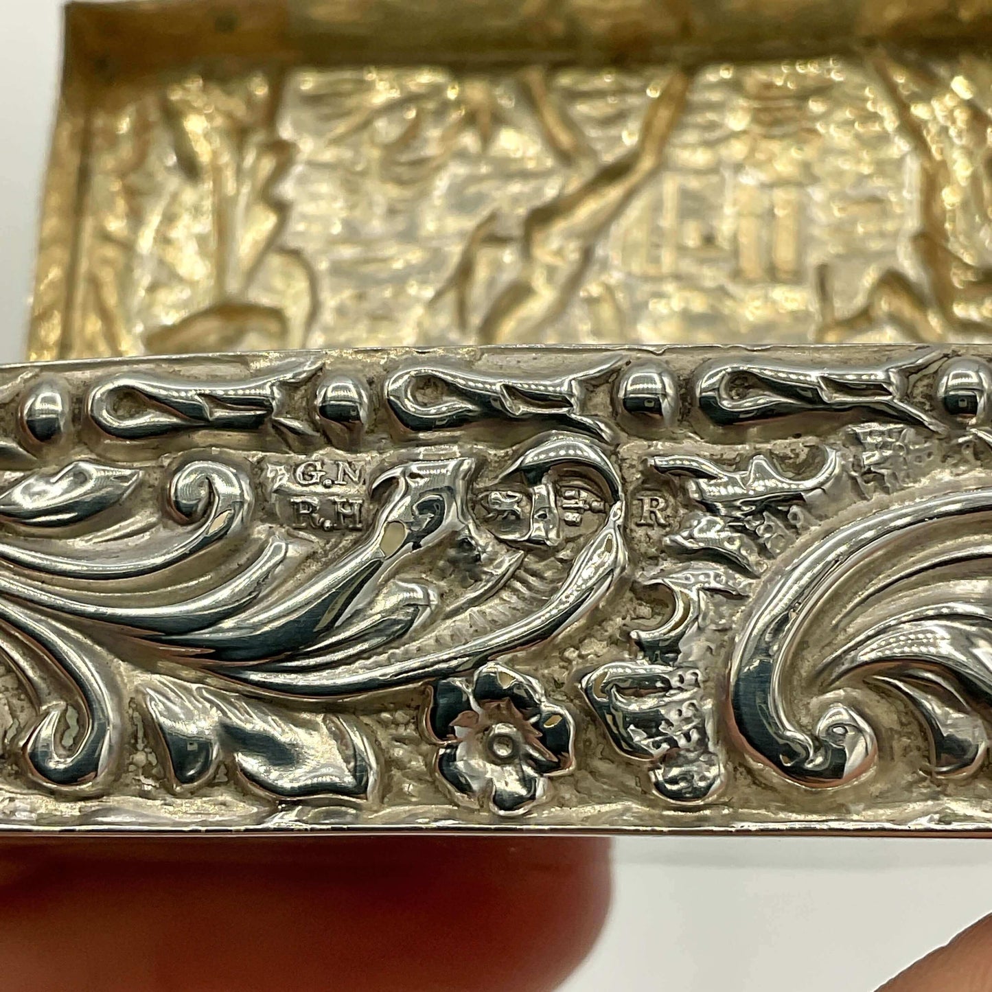 Close-up of a silver decorative  box with intricate patterns and engraved text.