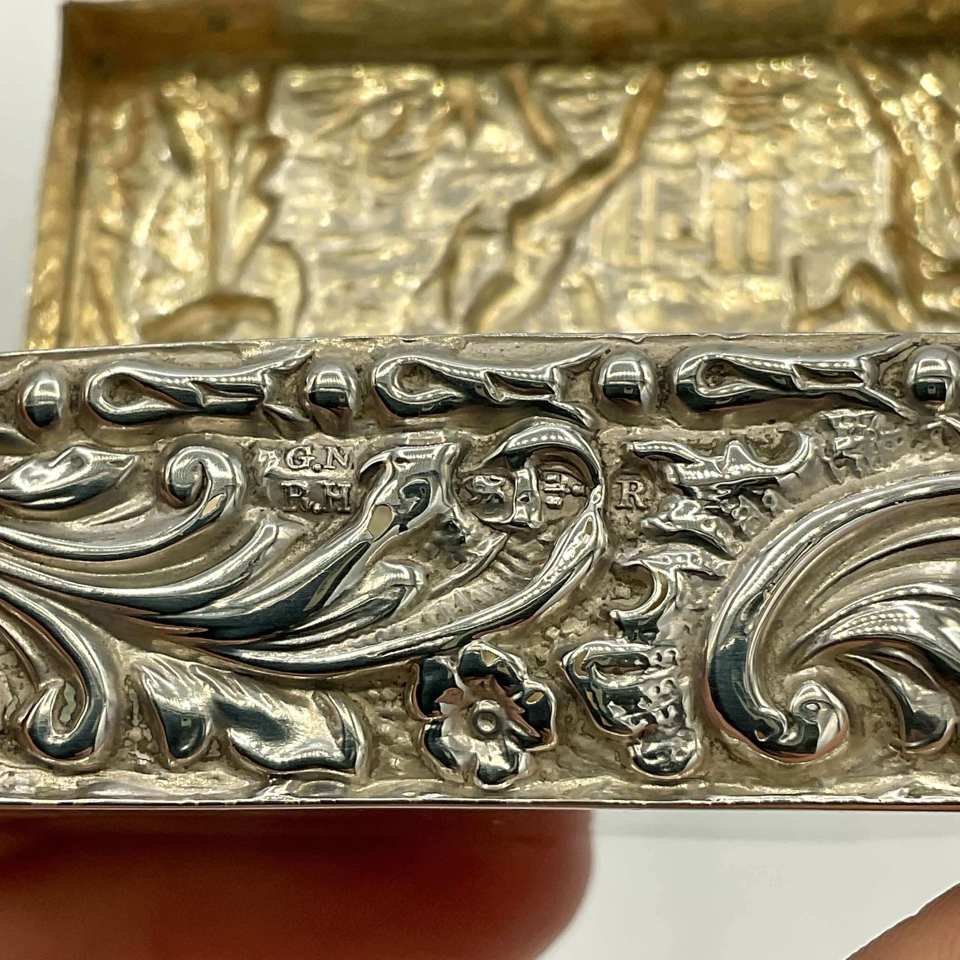 Close-up of a silver decorative  box with intricate patterns and engraved text.