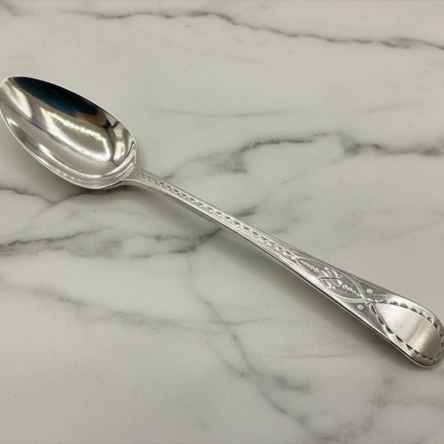 Antique Georgian sterling silver teaspoon with hallmarks from 1793, featuring intricate detailing and classic design.