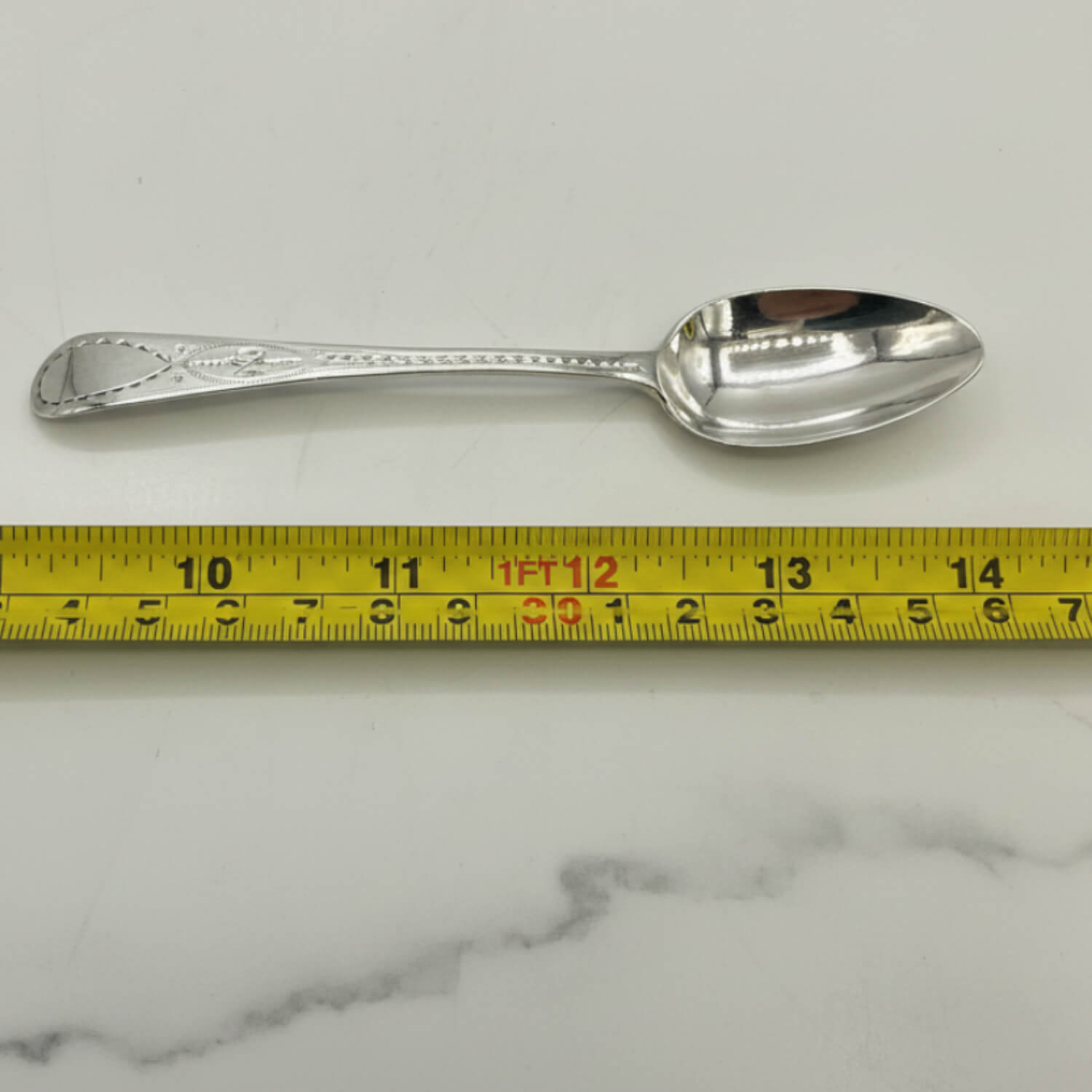 Antique Georgian sterling silver teaspoon with hallmarks from 1793, featuring intricate engraved details.