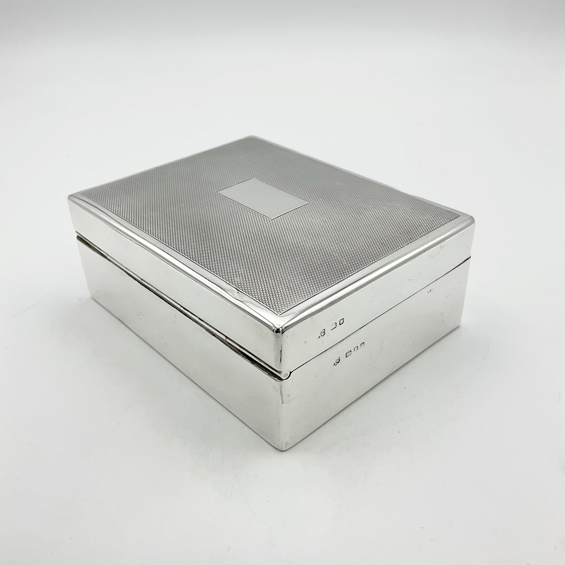 Silver cigarette box with the view of the back hinge and hallmarks at the side