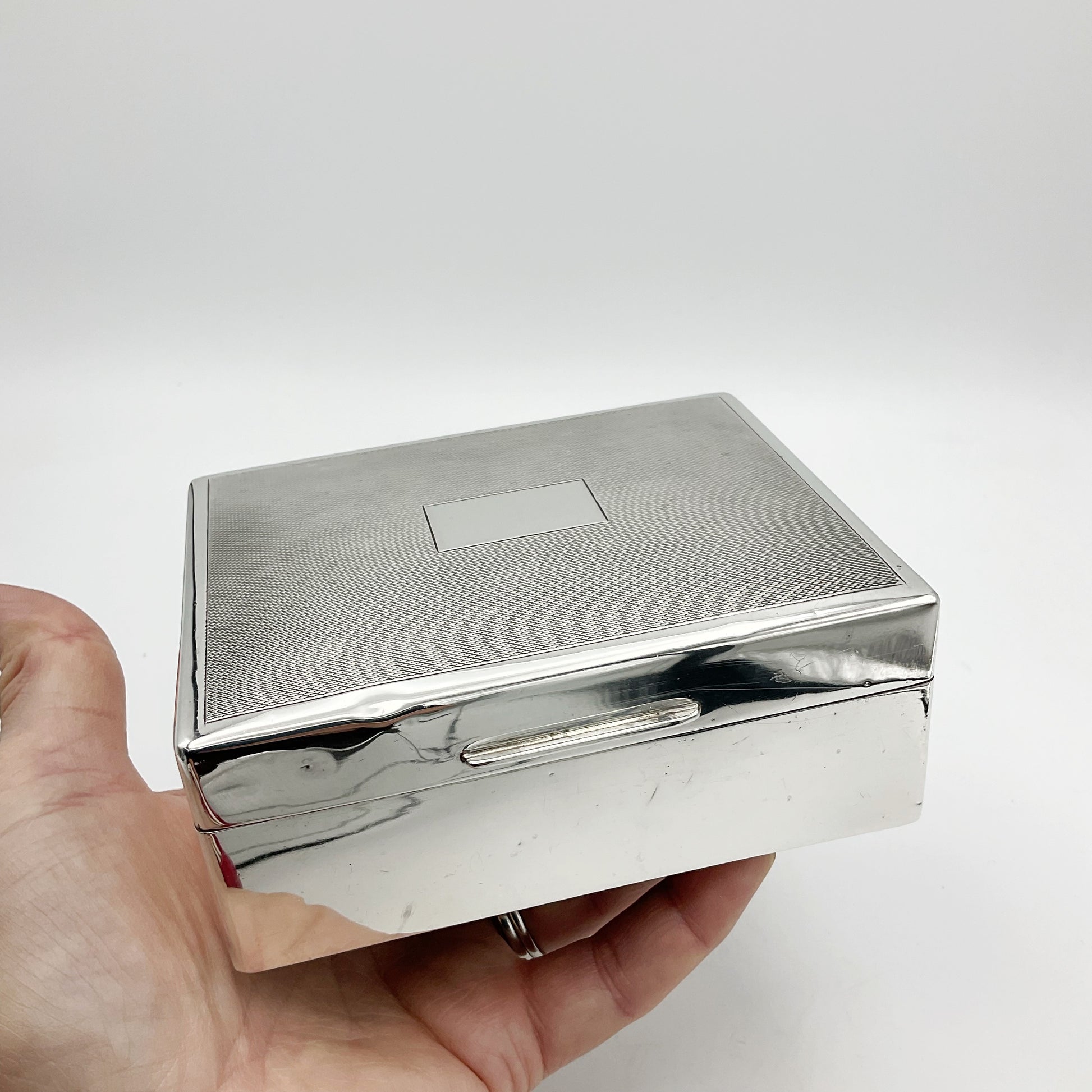Shiny vintage silver cigarette box held in a hand