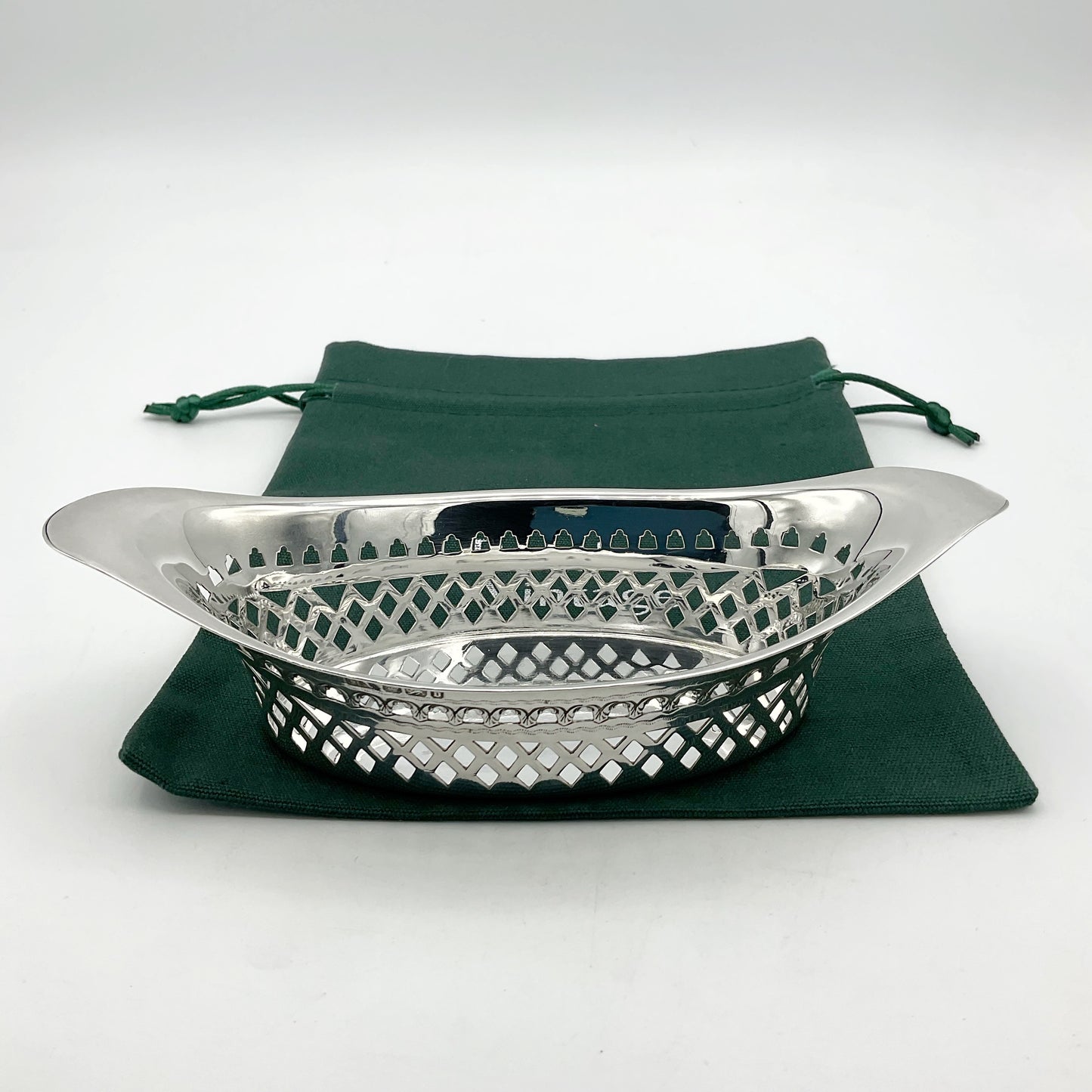 Silver boat shaped pierced bowl on green cotton bag