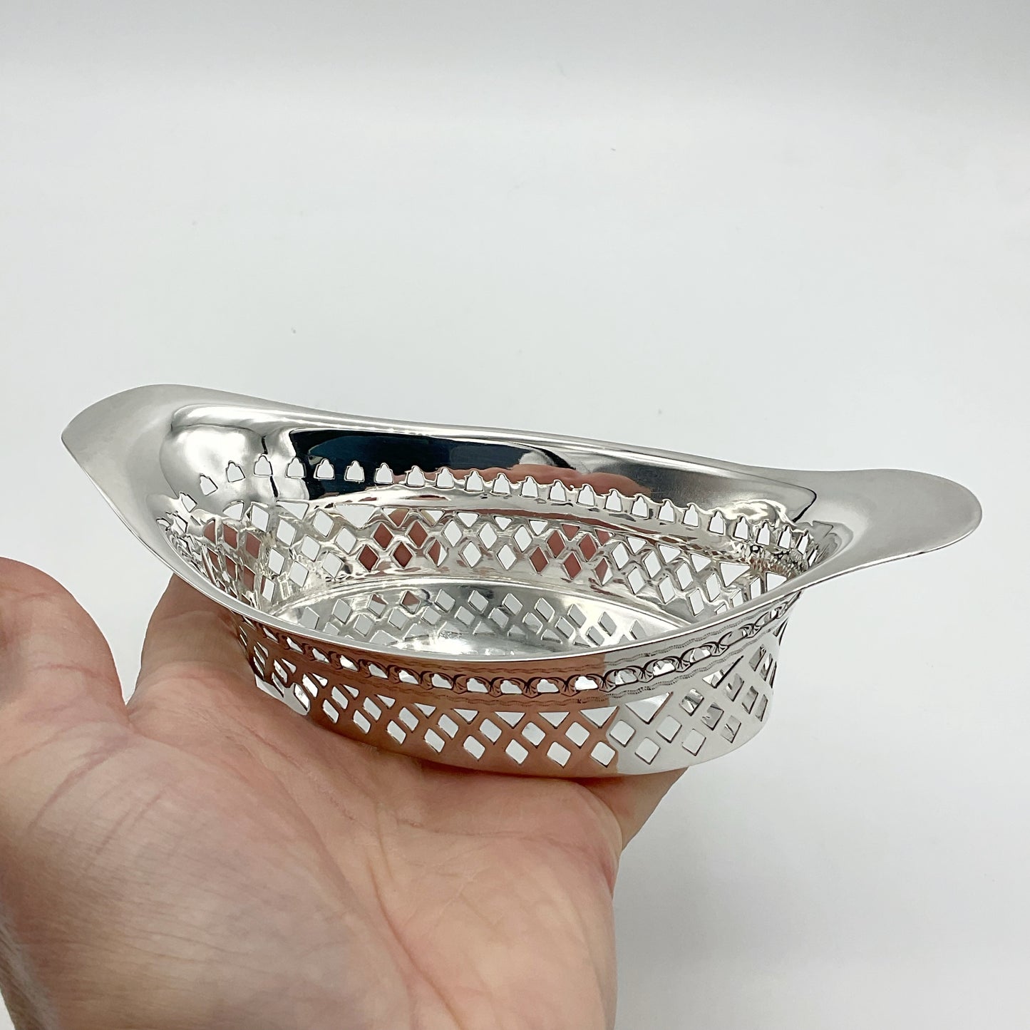 Shiny silver pierced bowl sitting on a hand