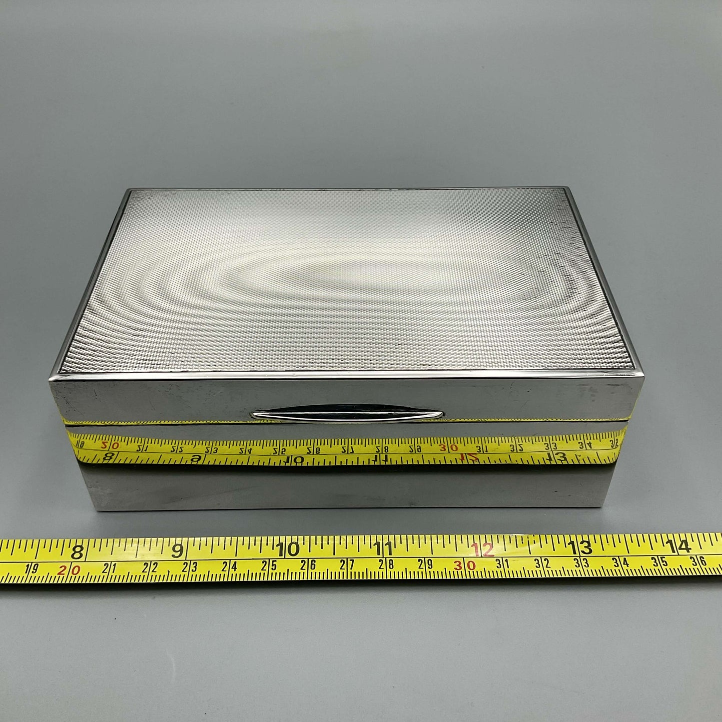 1960s Silver cigarette box next to tape measure showing width as approx 14cm