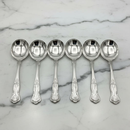 six silver plated soup spoons on a marble worktop