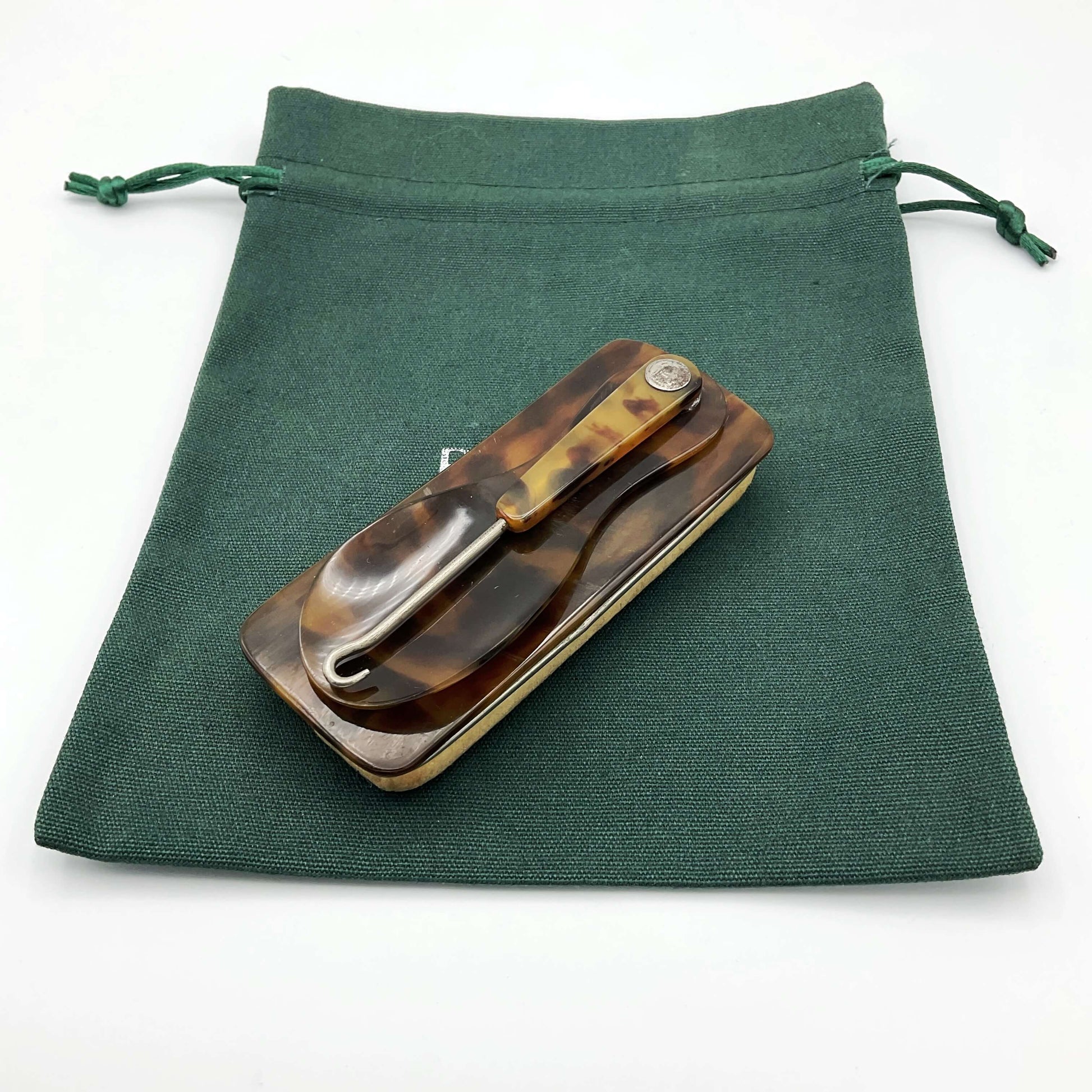 Vintage Shoe Horn Hook and Buffer on a green cotton bag