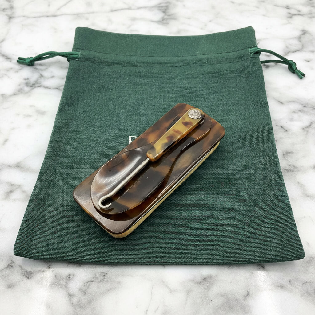 Vintage Shoe Horn Hook and Buffer on a green cotton bag on a marble surface