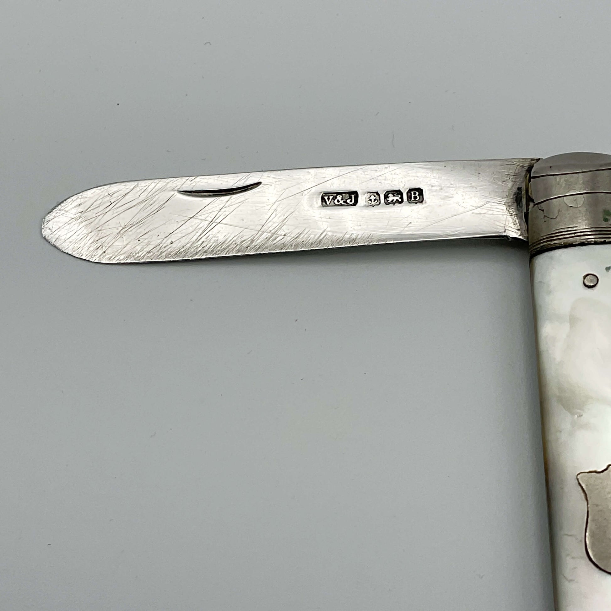 Silver blade of a fruit knife with hallmarks.