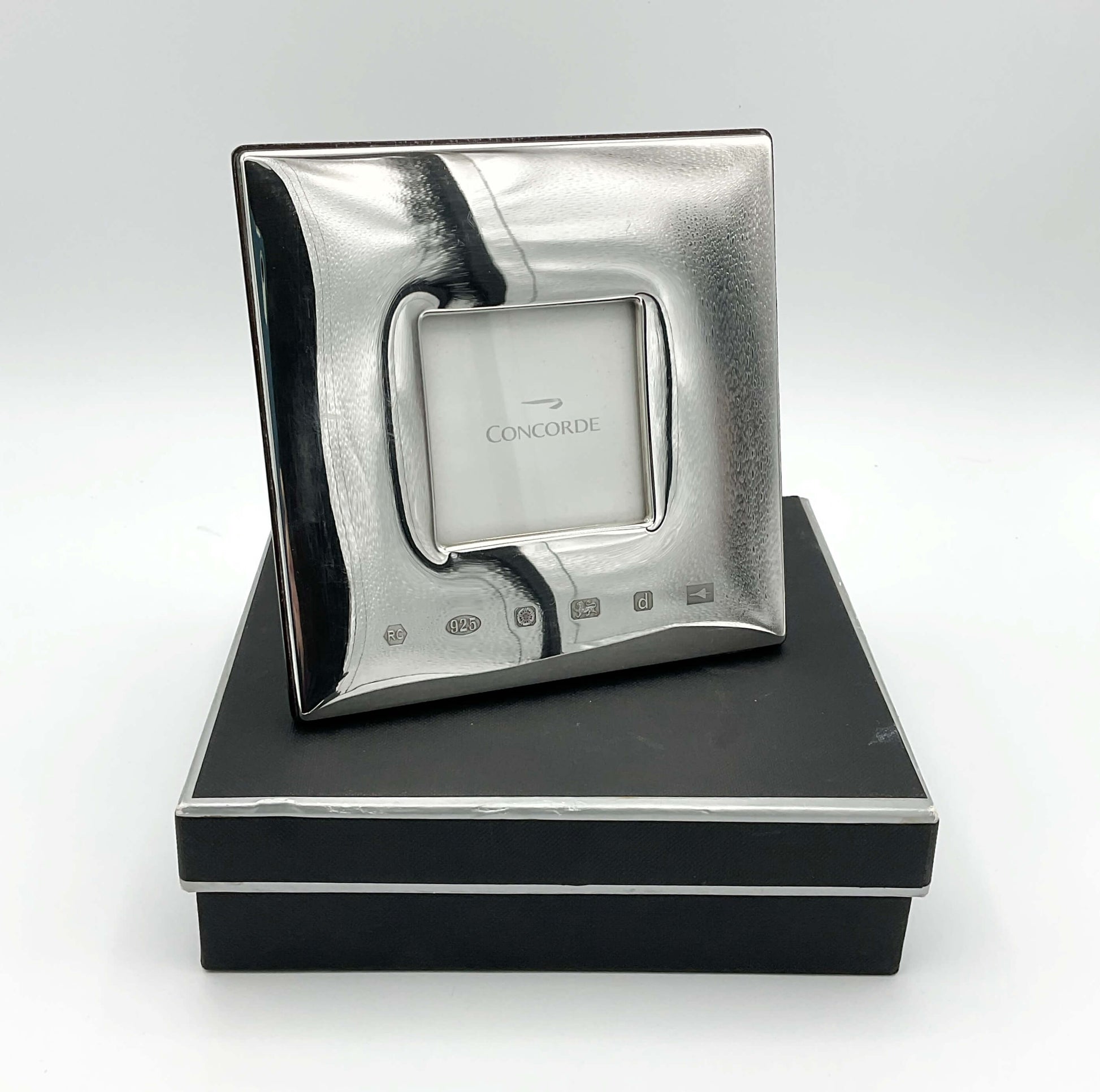 Silver picture frame with Concorde printed in the middle standing on a brown presentation box