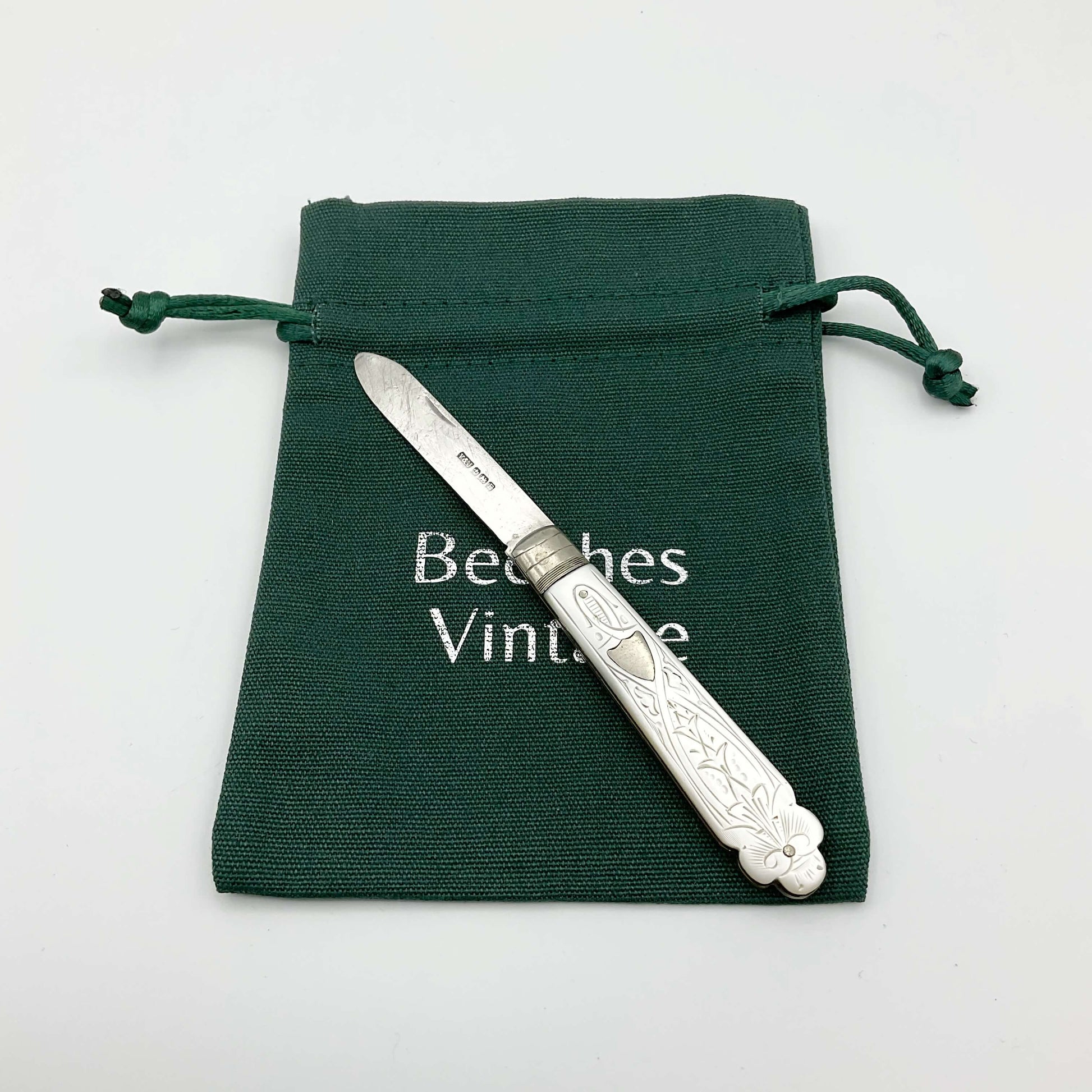 Vintage silver fruit knife with a beautifully engraved mother of pearl handle on a green gift bag