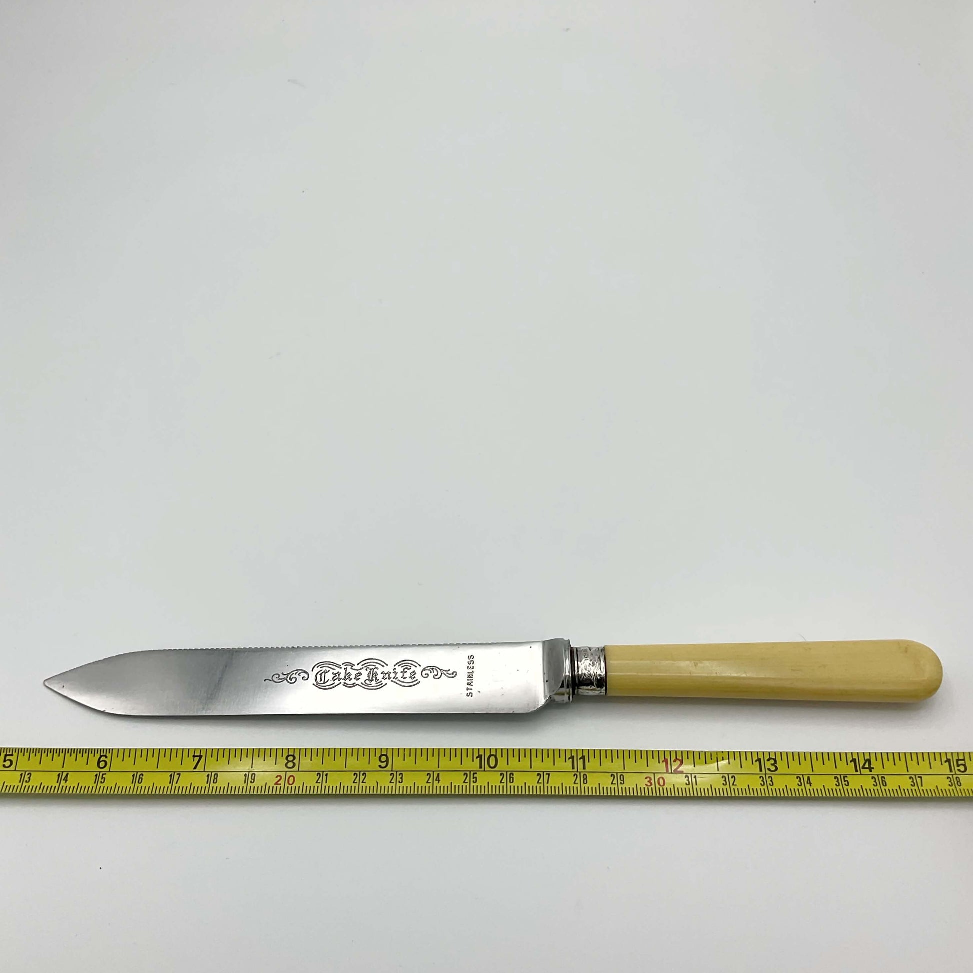 Vintage cake knife next to tape measure showing it’s 10 inches in length.