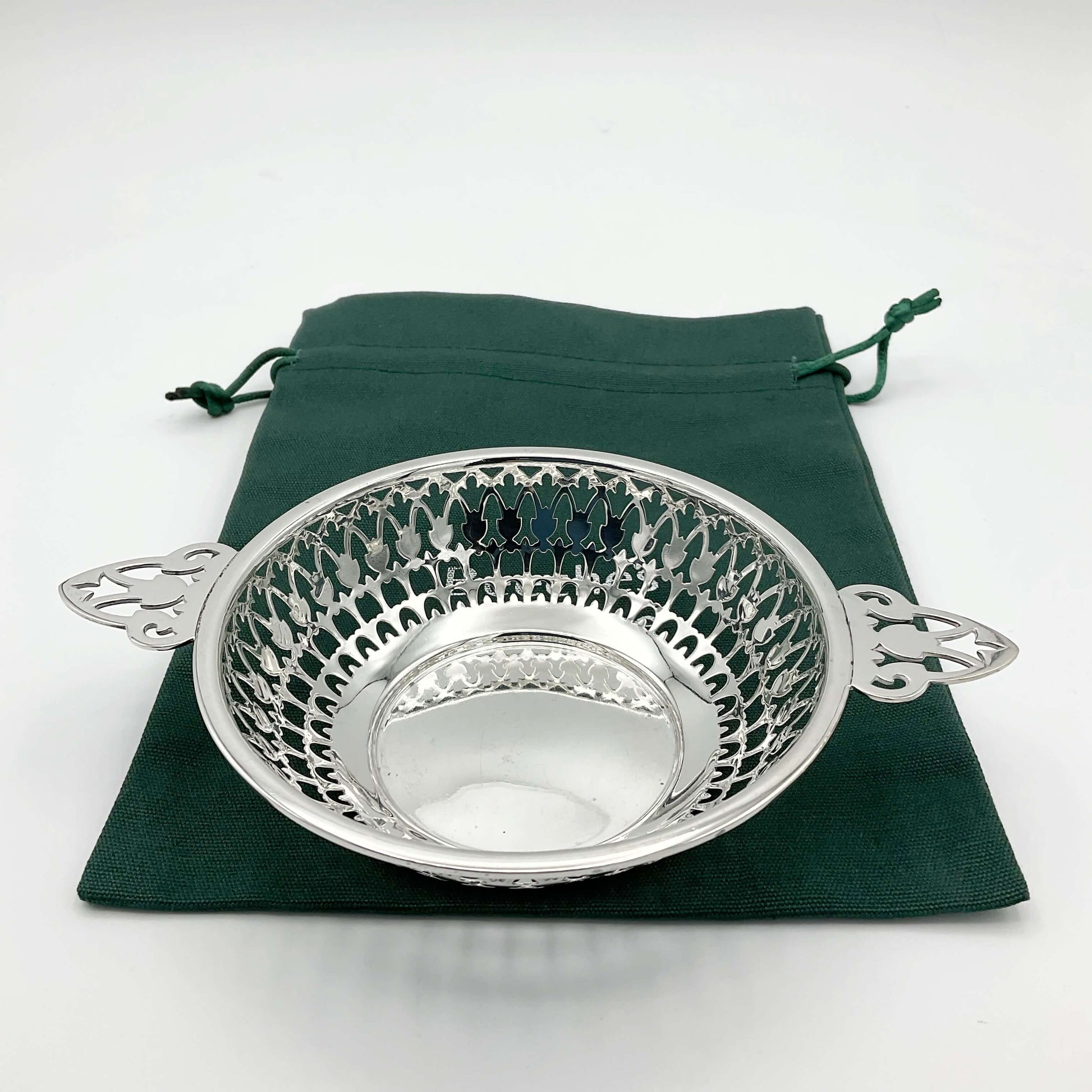 Shiny silver pierced bowl with handles on green cotton gift  bag