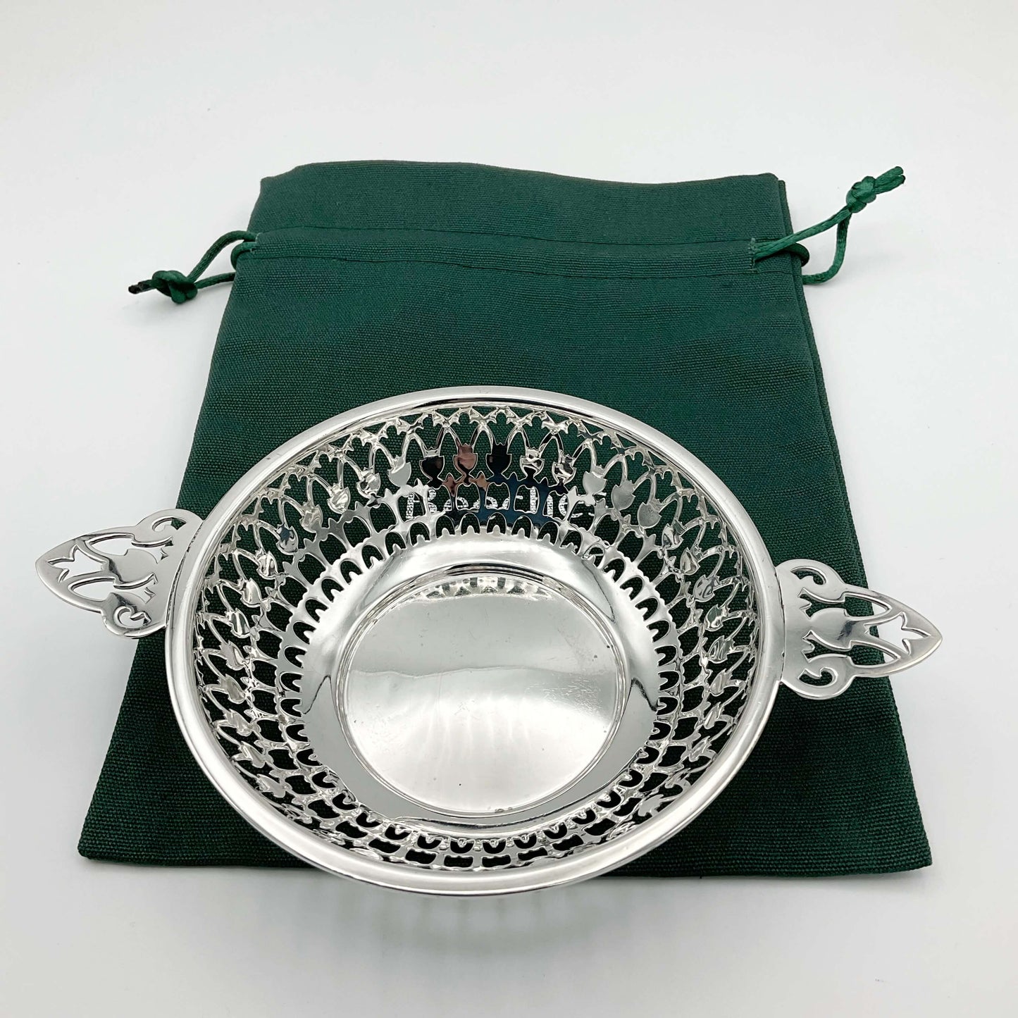 Shiny silver pierced bowl with handles on green cotton gift  bag