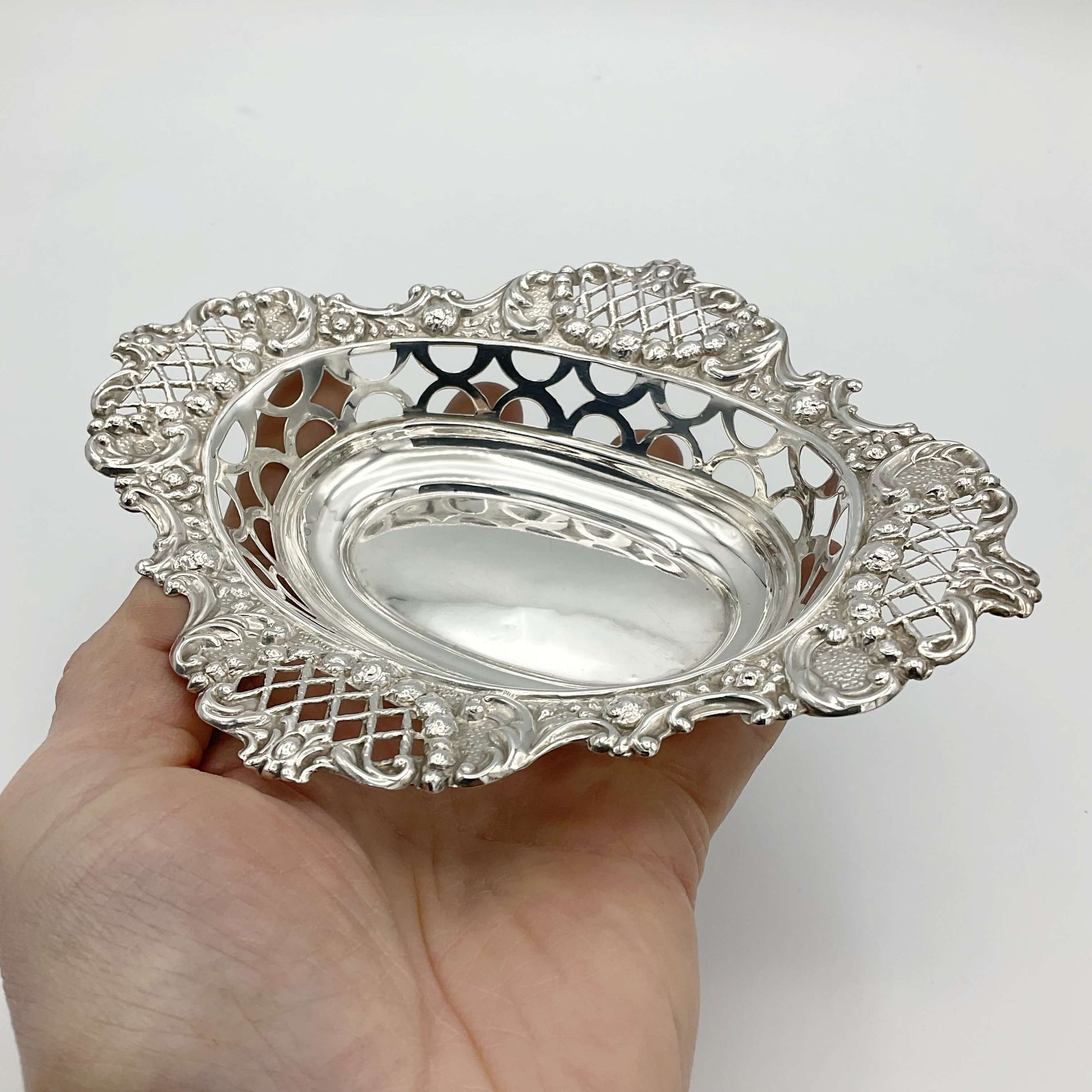 Beautiful detailing shown on the silver pierced bowl held in a hand