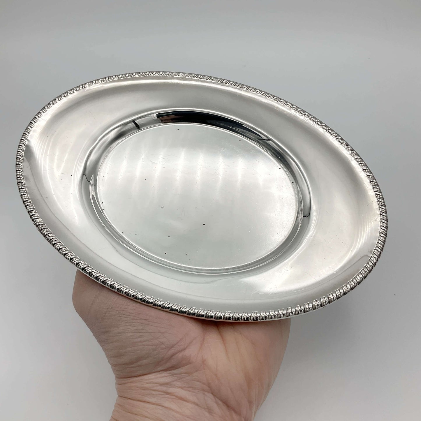 A beautiful shiny silver plated serving tray or platter held on a hand on a white background