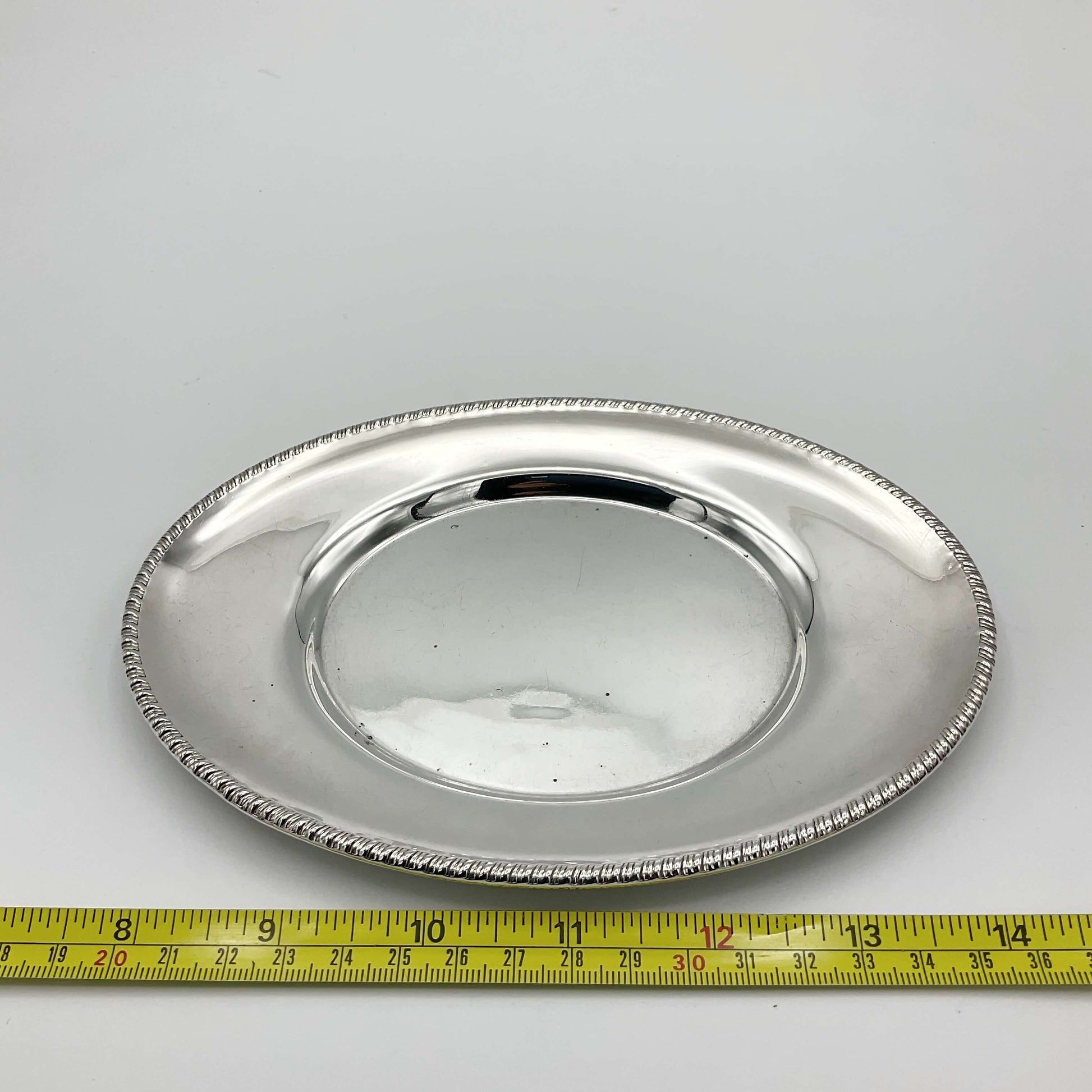 Silver plated tray next to tape measure showing size as approximately 16cm
