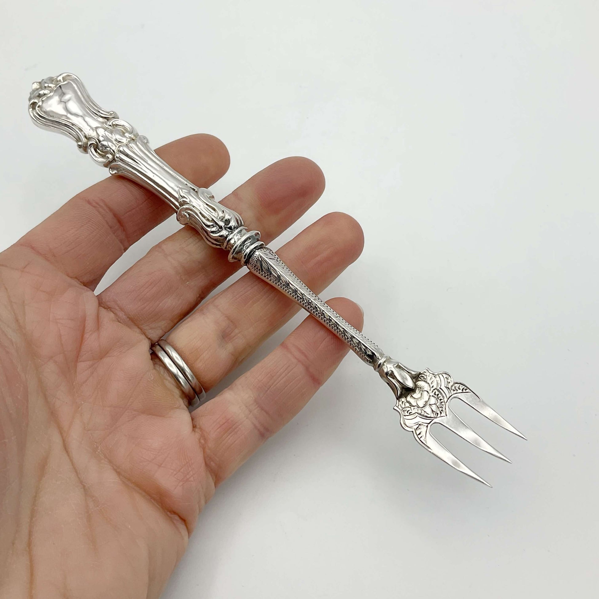 Antique Silver pickle fork held in hand