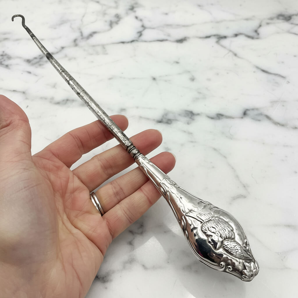 Beautiful large antique silver button hook featuring a cherub on the handle across a hand