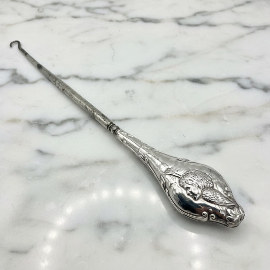 Beautiful large antique silver button hook featuring a cherub on the handle on a marble worktop