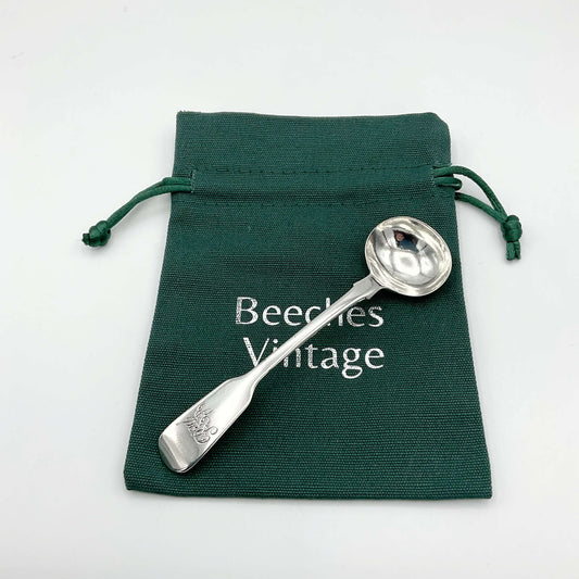 Antique silver condiment spoon on a green gift bag