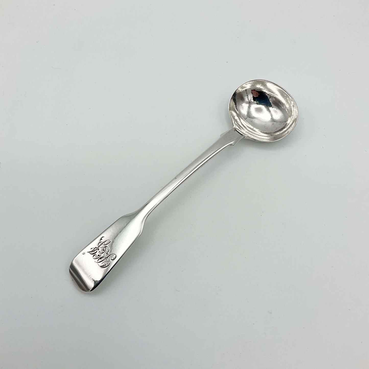 Antique silver condiment spoon on a white background 