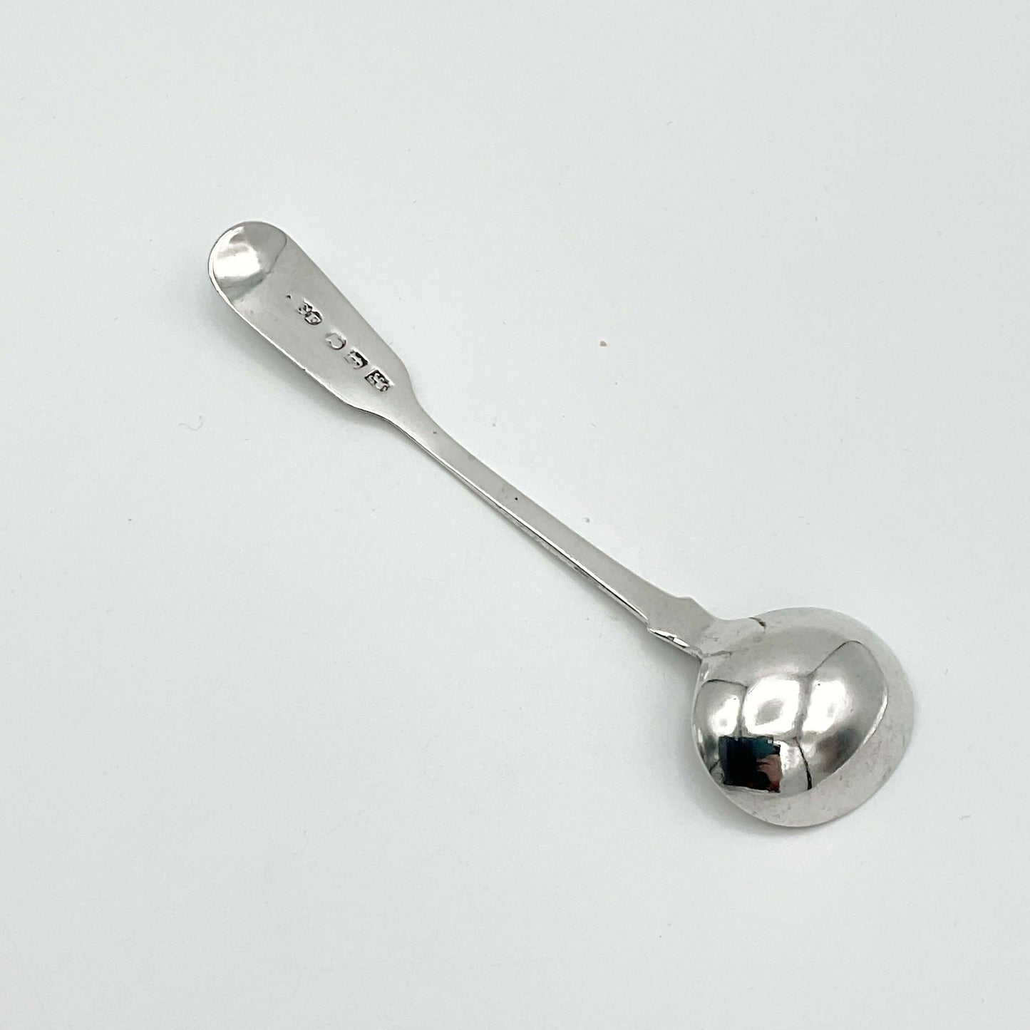 Back of Antique silver condiment spoon on a white background