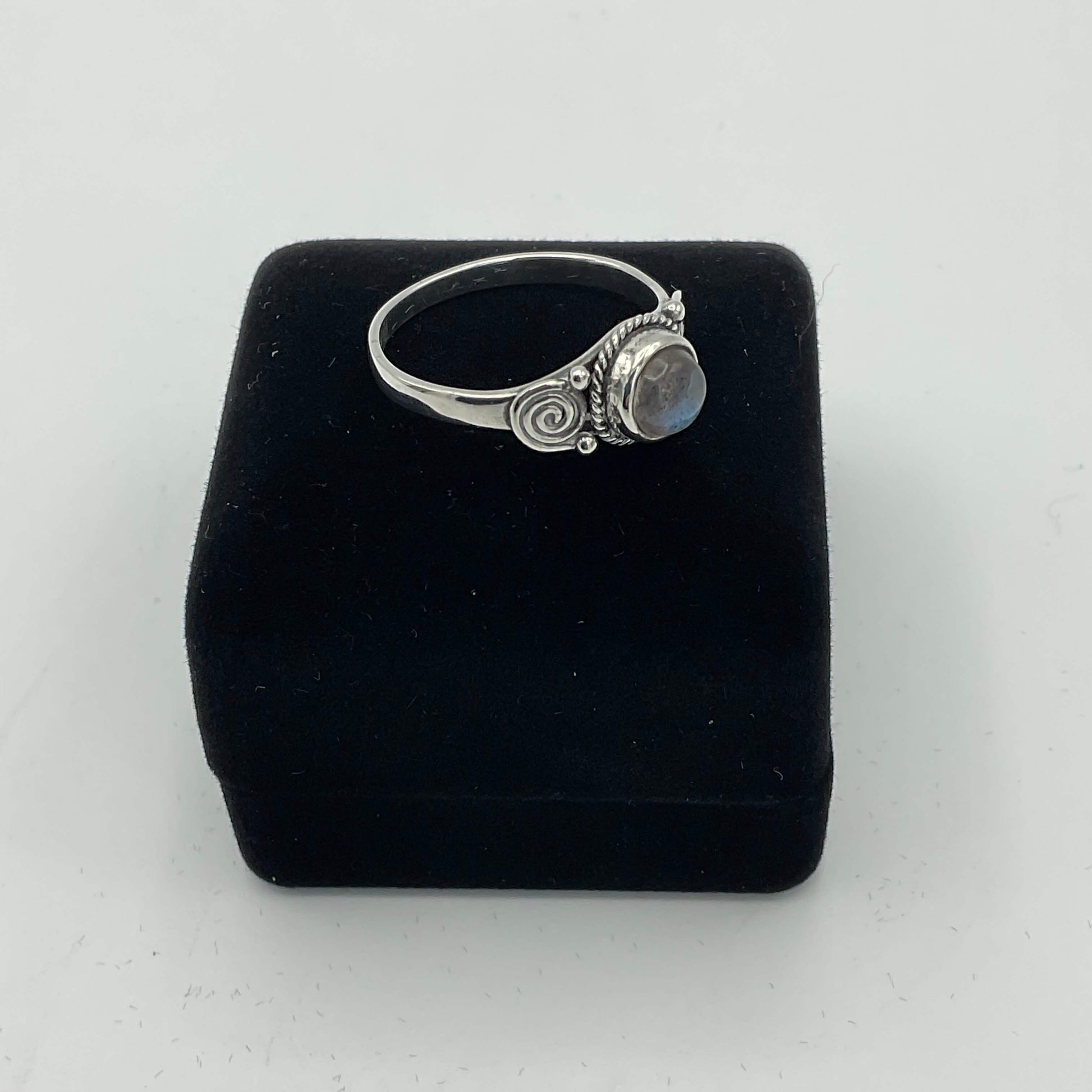 A moonstone silver ring sitting on a black presentation ring box