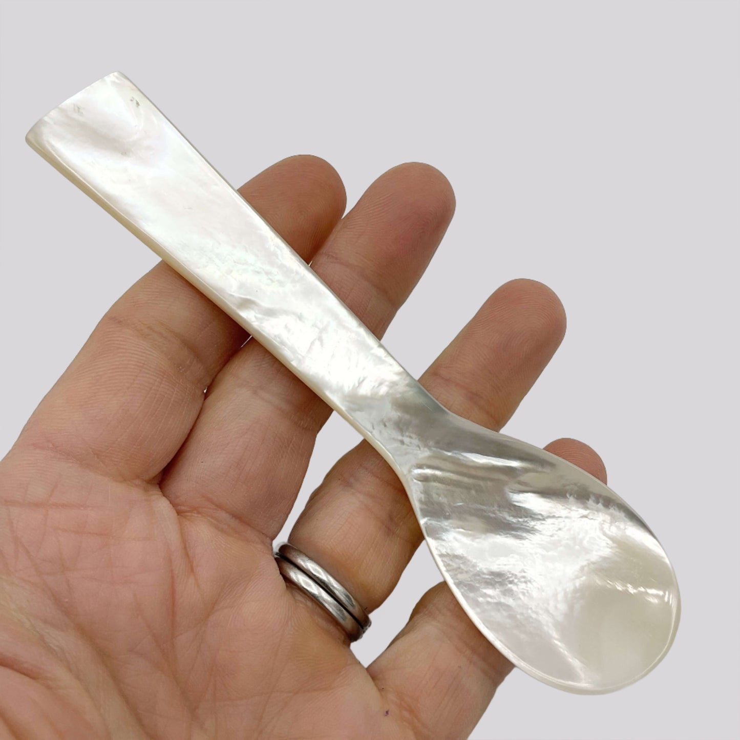 Mother of Pearl spoon held in a hand