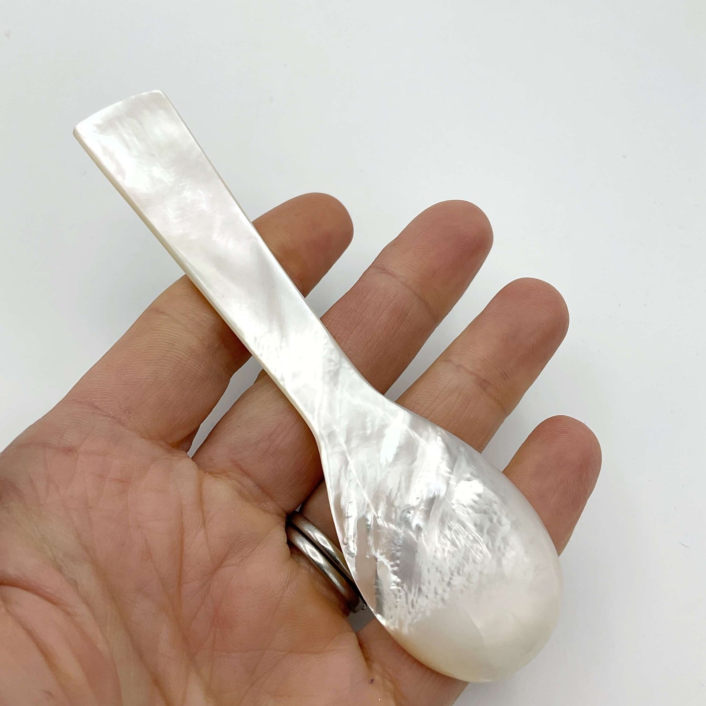 Back of a mother of pearl spoon on a hand 