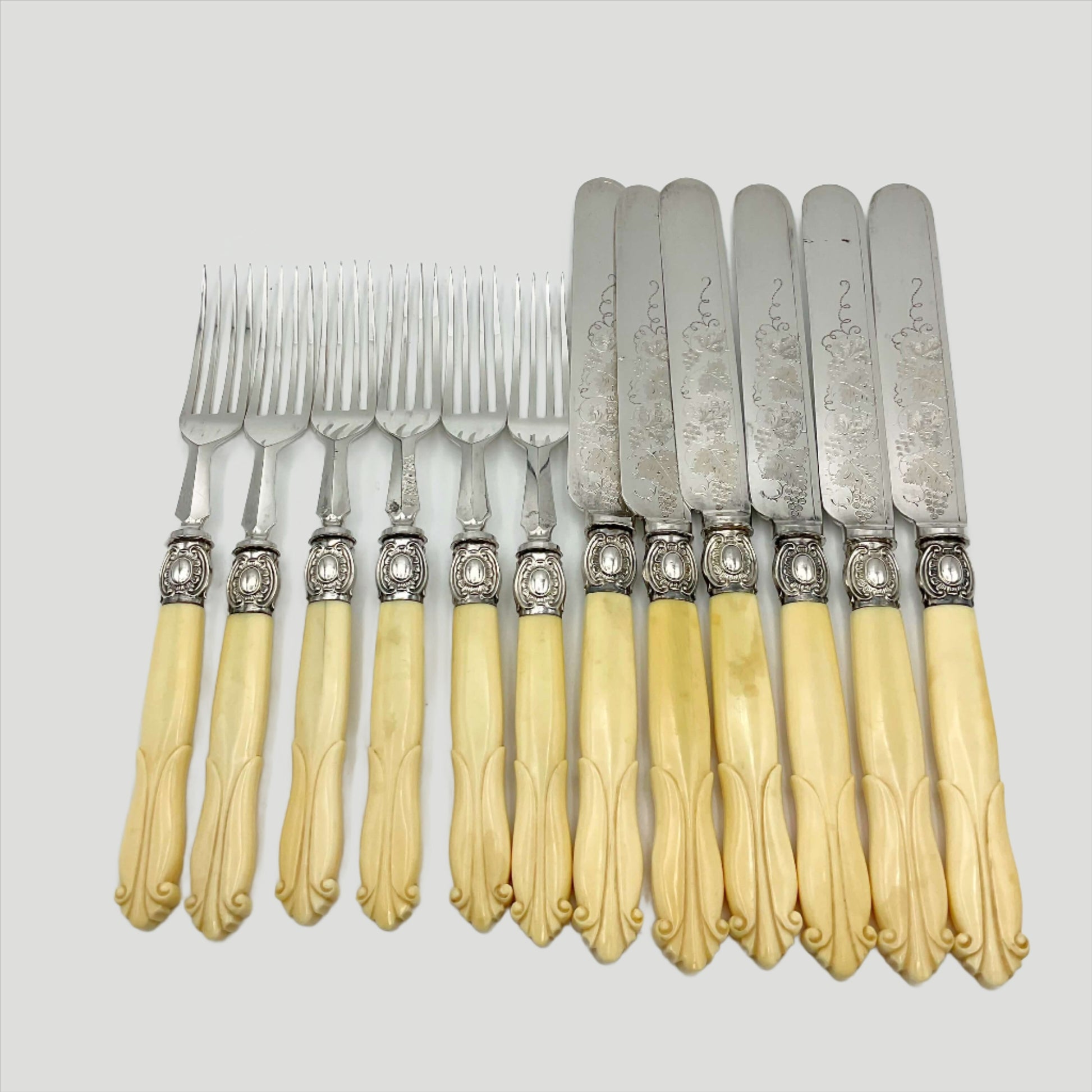 Antique silver plated dessert knives and forks with bone handles on a white background