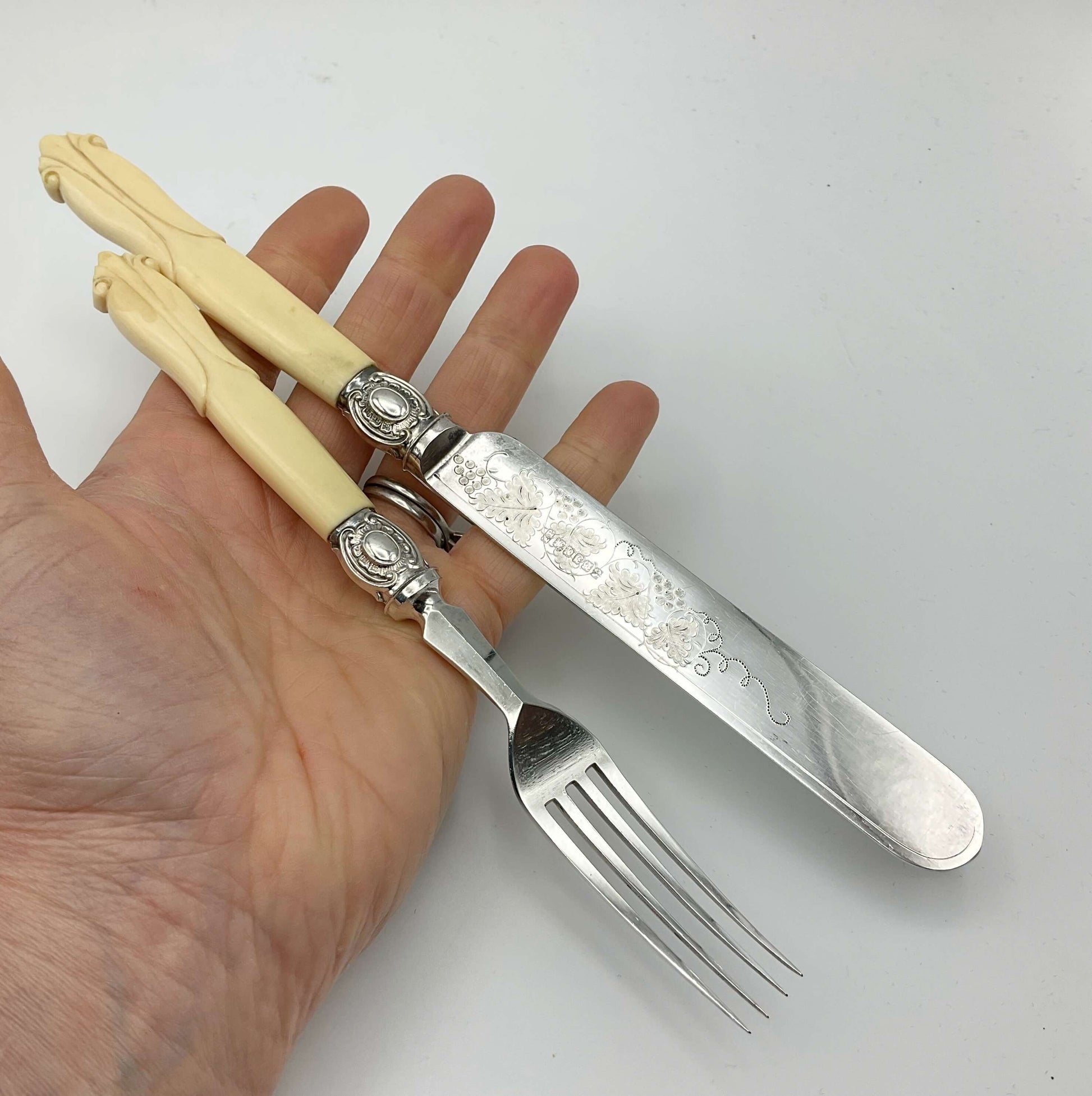 an antique silver plated knife and fork with bone handles held in a hand