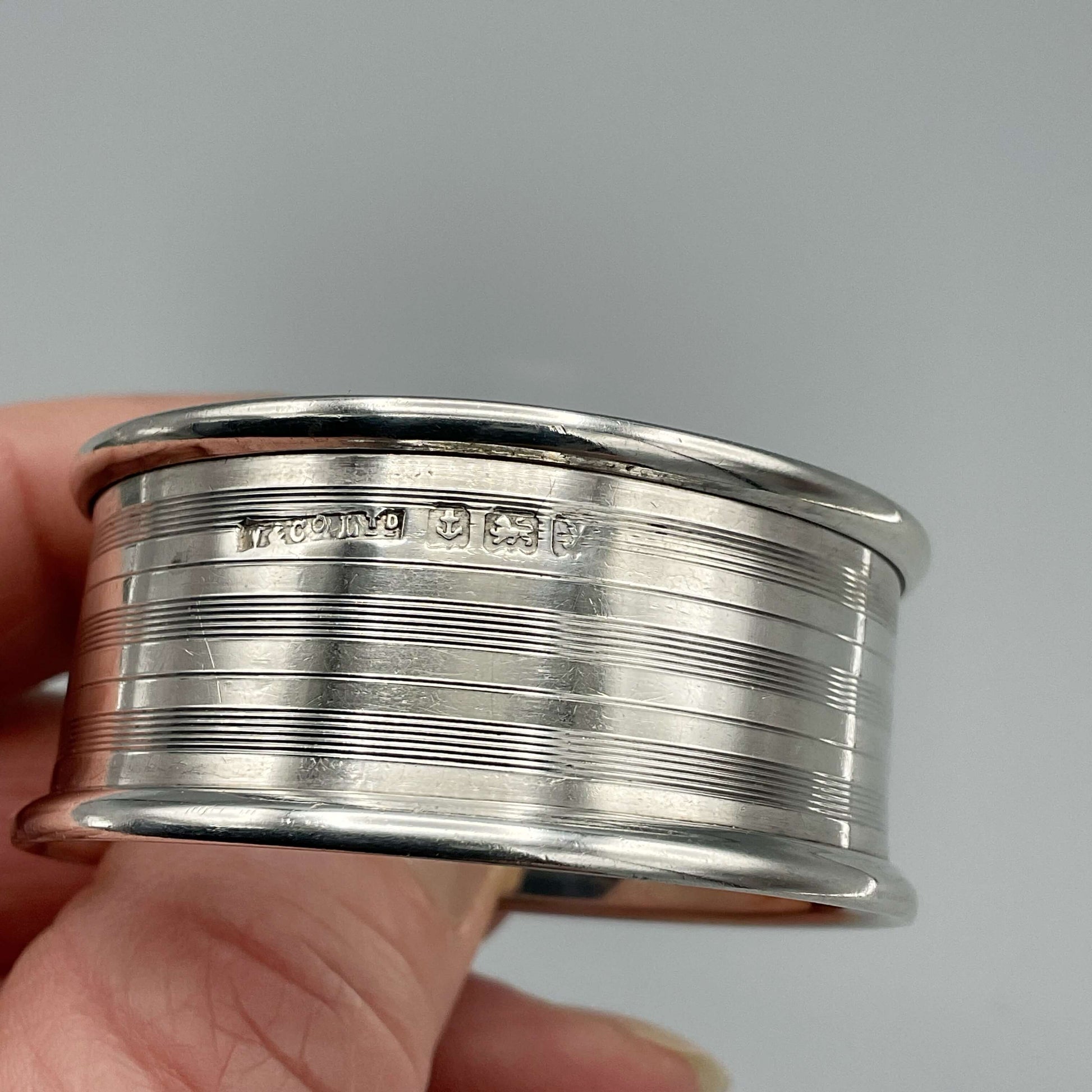Silver napkin ring showing the hallmarks held in a hand