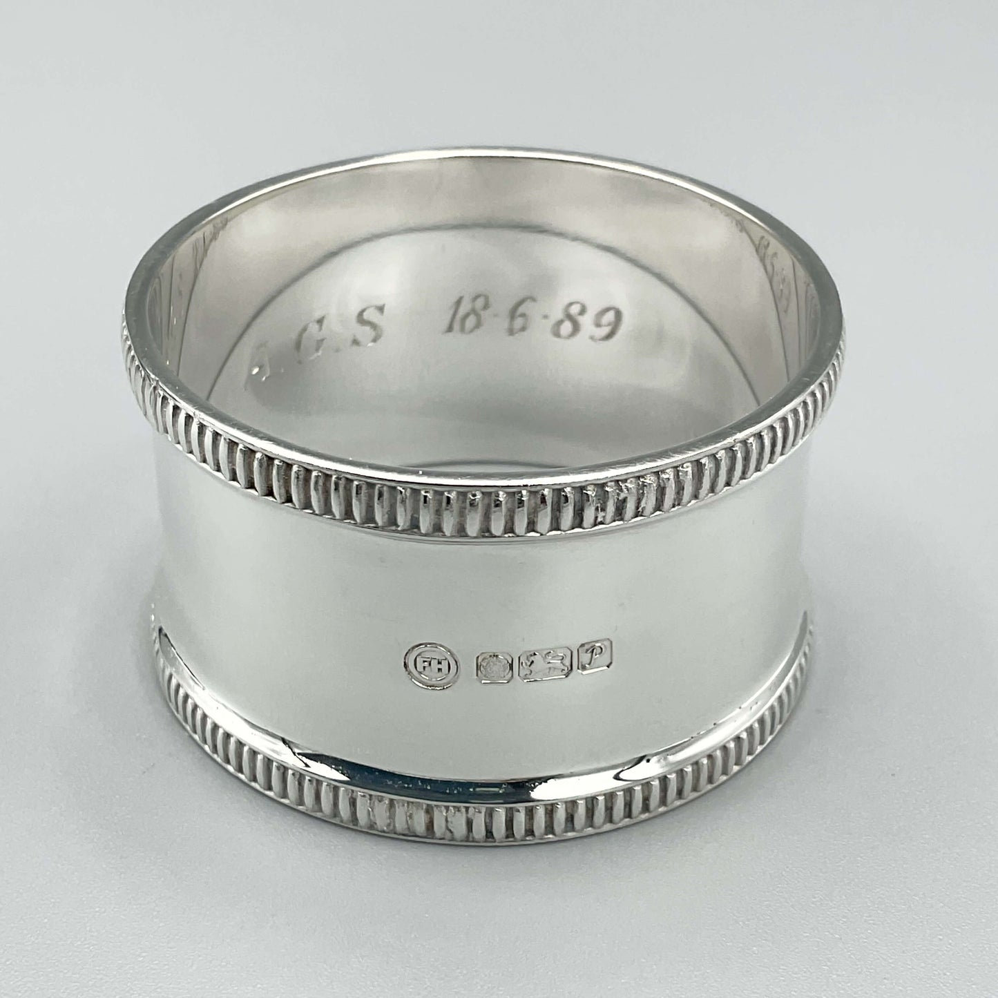 Shiny silver napkin ring showing the hallmarks and internal engraving 