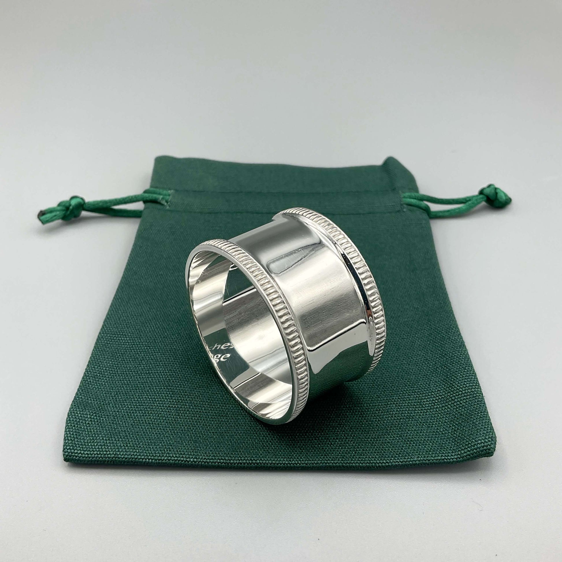 Shiny silver napkin ring on a green cotton gift bag