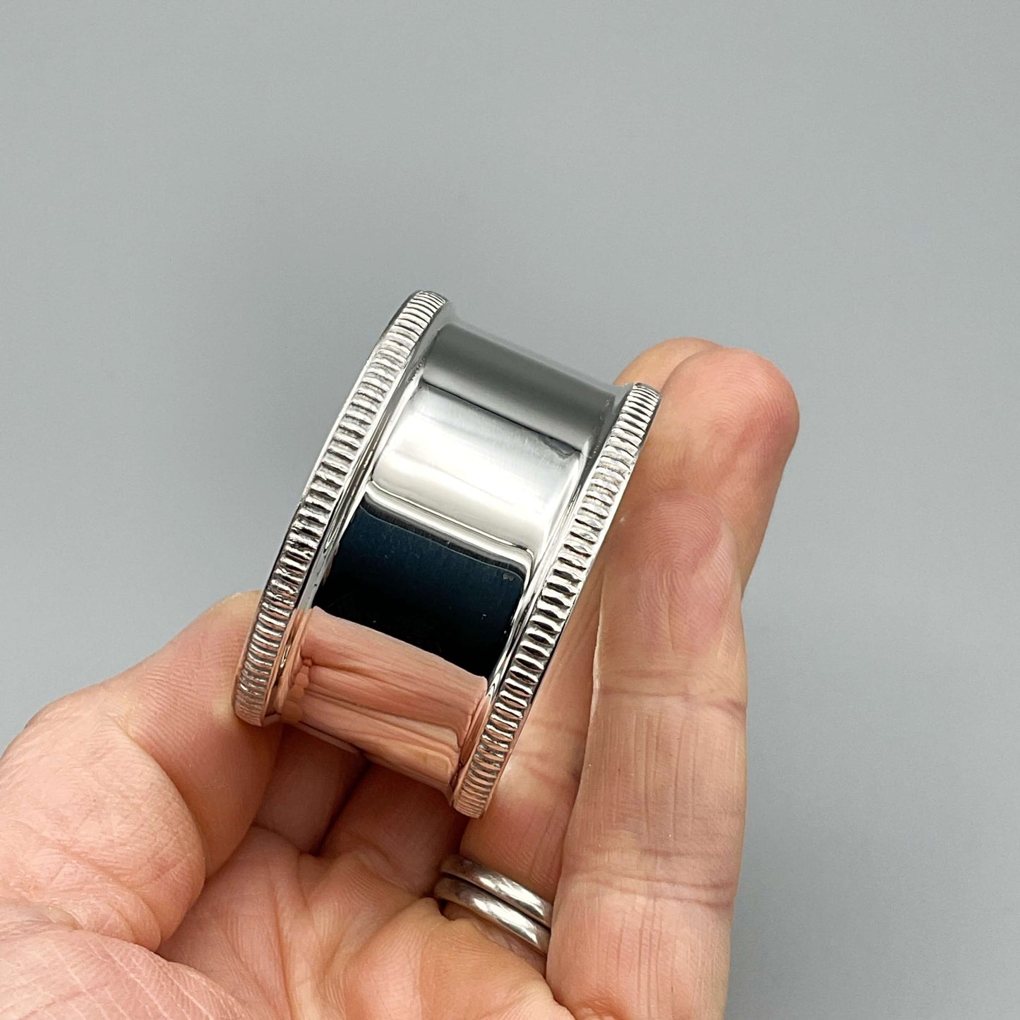 Shiny silver napkin ring held in a hand