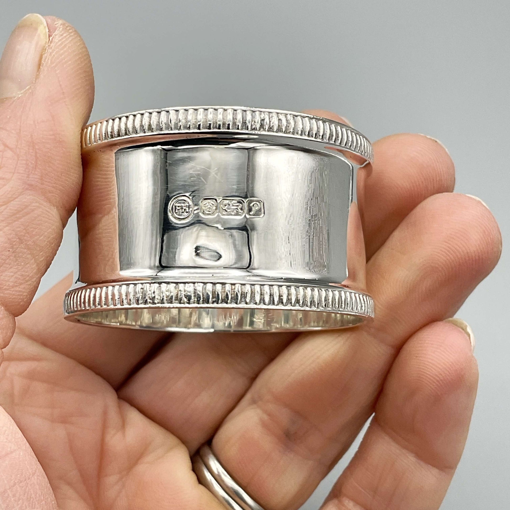 Shiny silver napkin ring showing Sheffield hallmarks held in a hand
