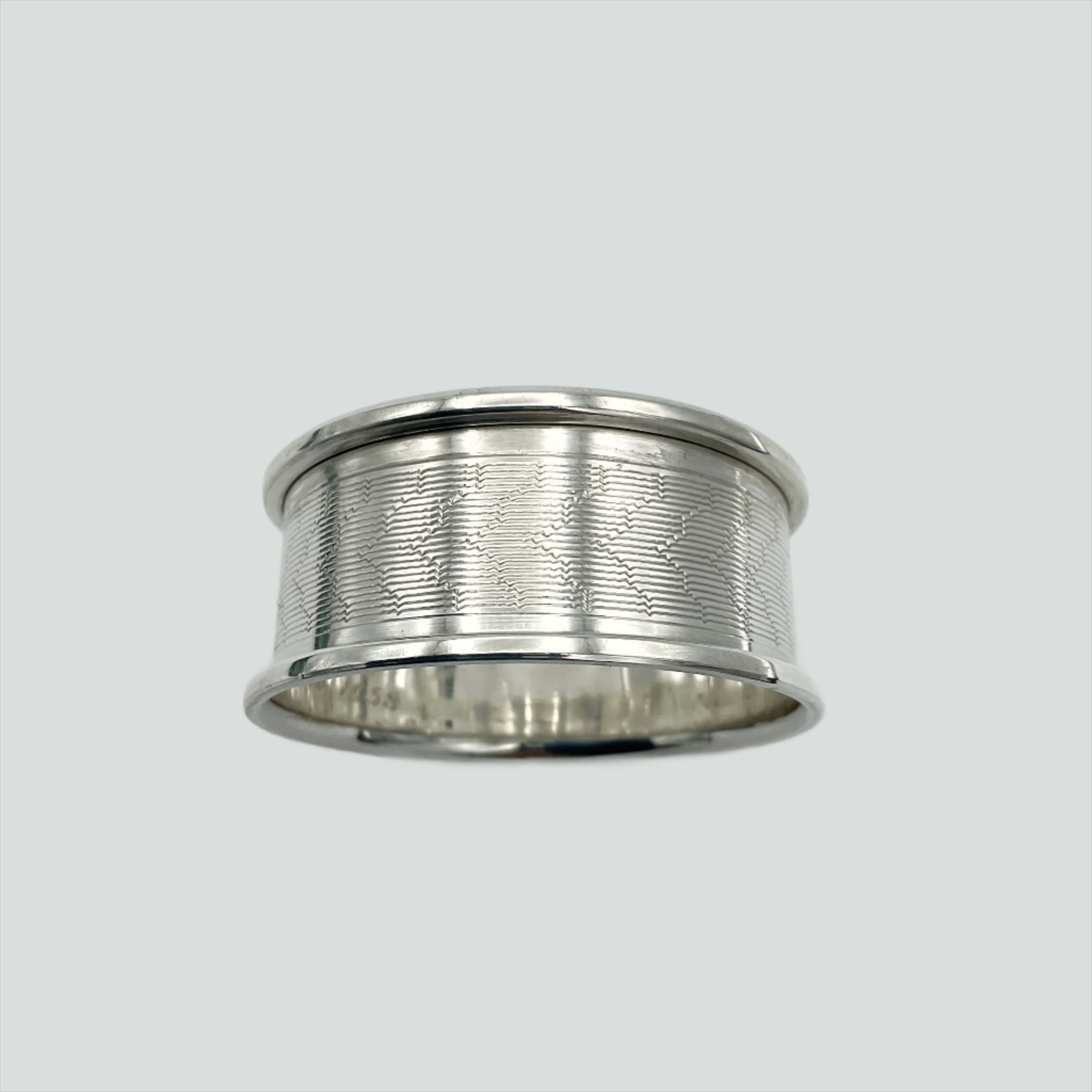Silver napkin ring with a pretty engraved design on a plain background 