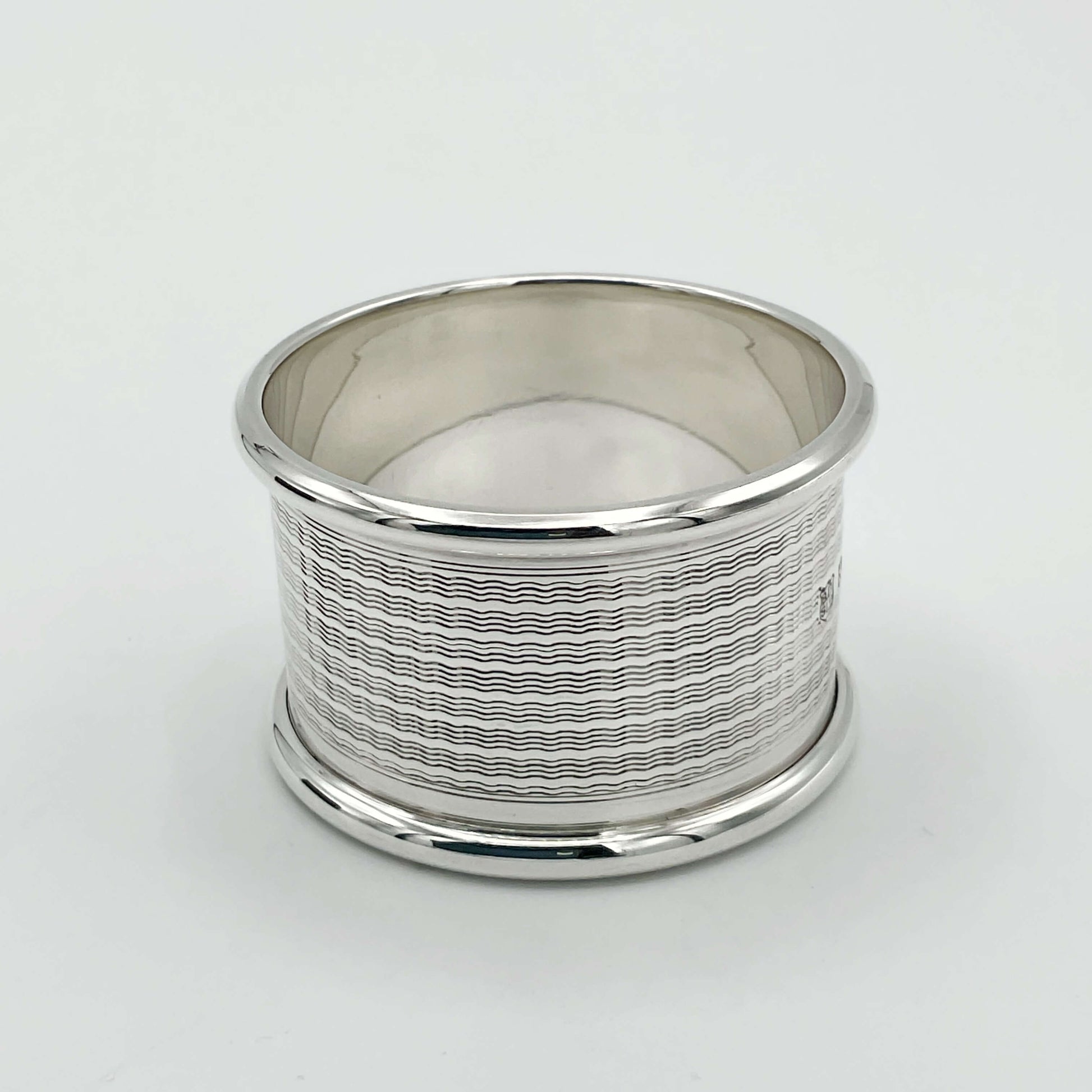 Beautiful lined design to the vintage silver napkin ring on a plain white background