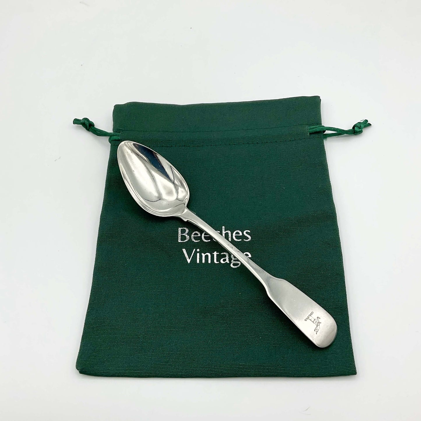 Silver dessert spoon on a green cotton gift bag