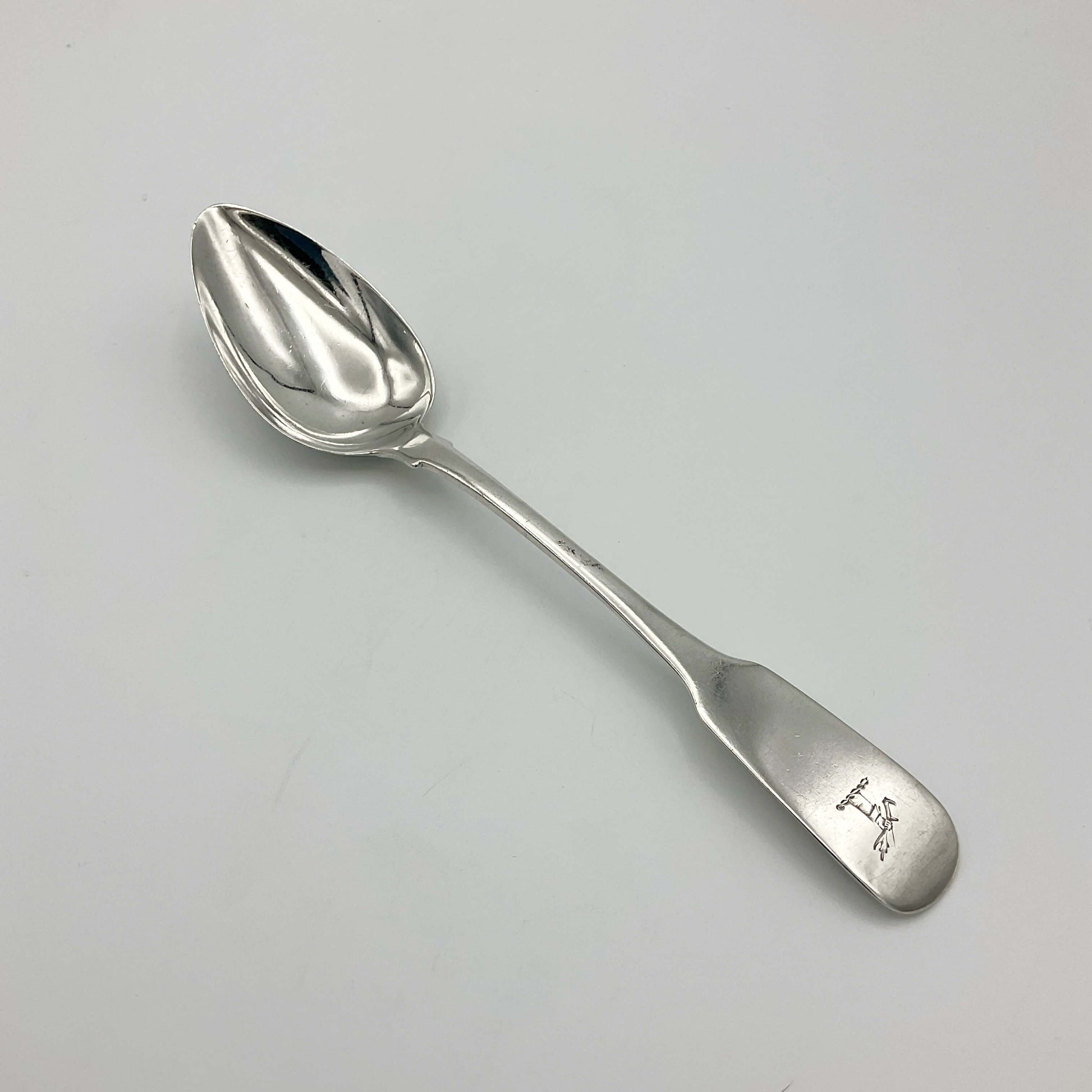 Silver dessert spoon on a plain background 