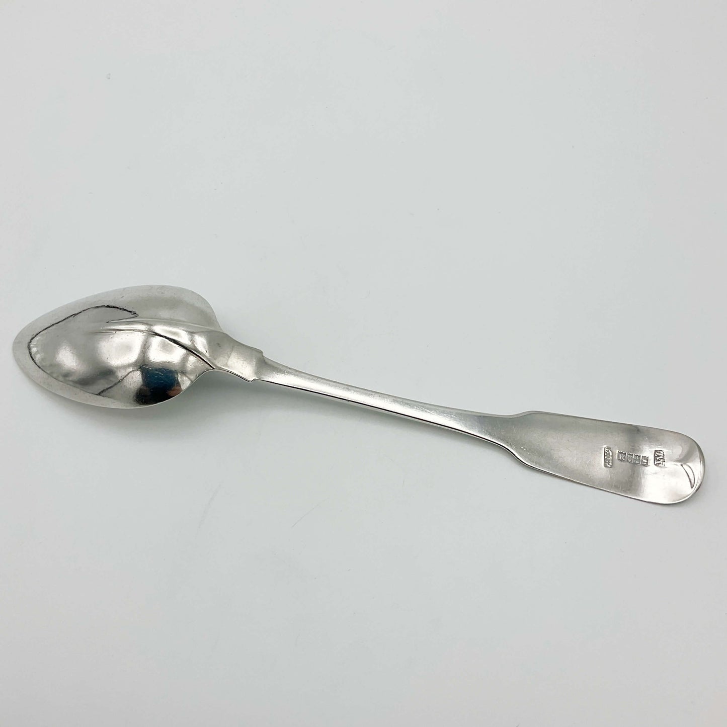 Back of Silver dessert spoon on a plain background 