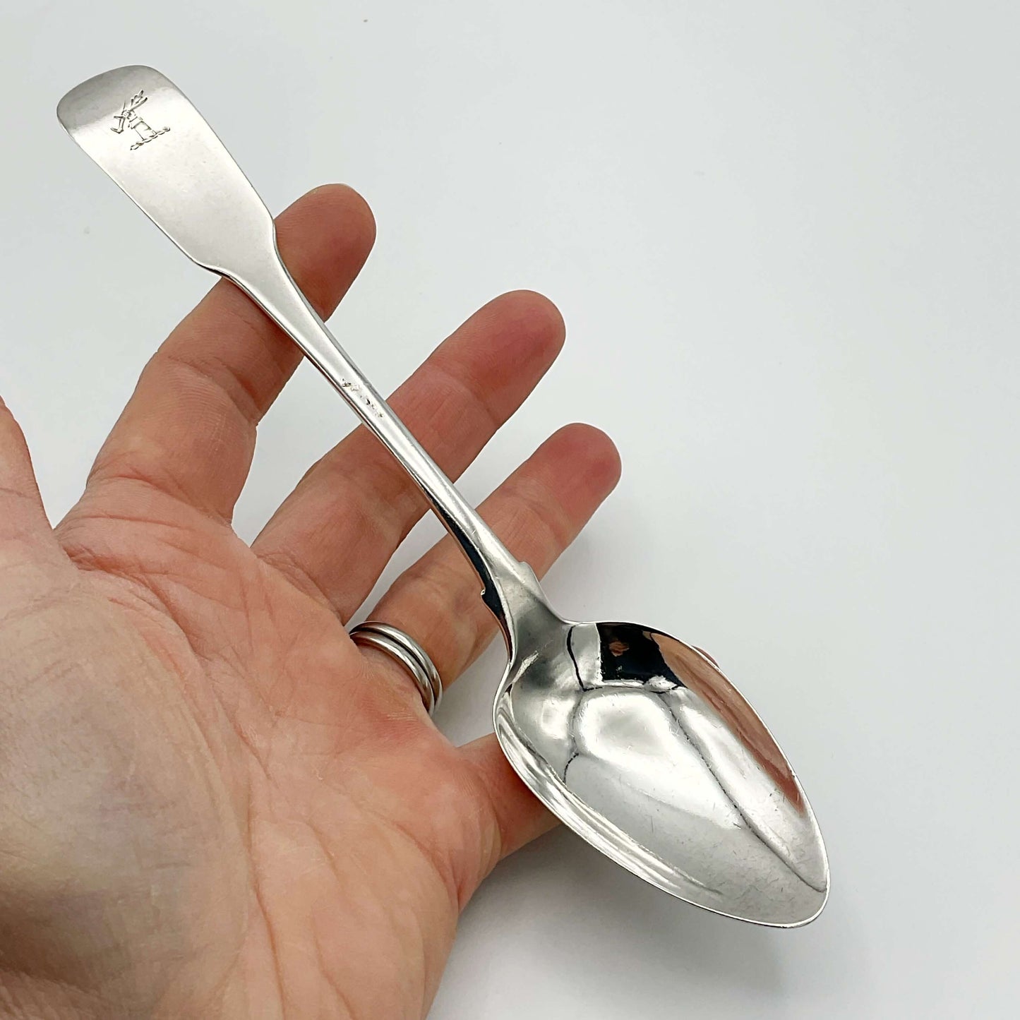Silver dessert spoon held in a hand