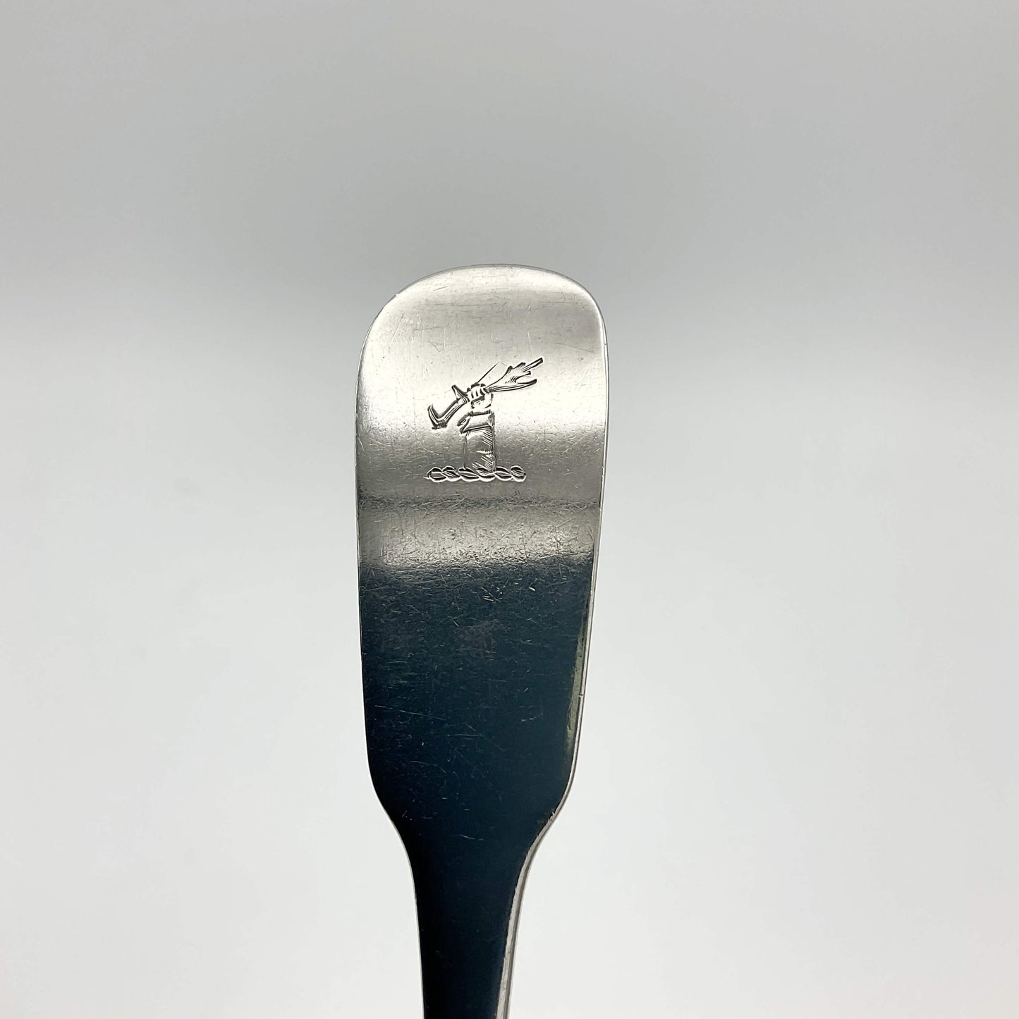 Top of handle of Antique silver spoon showing a motif of a hand holding an antler