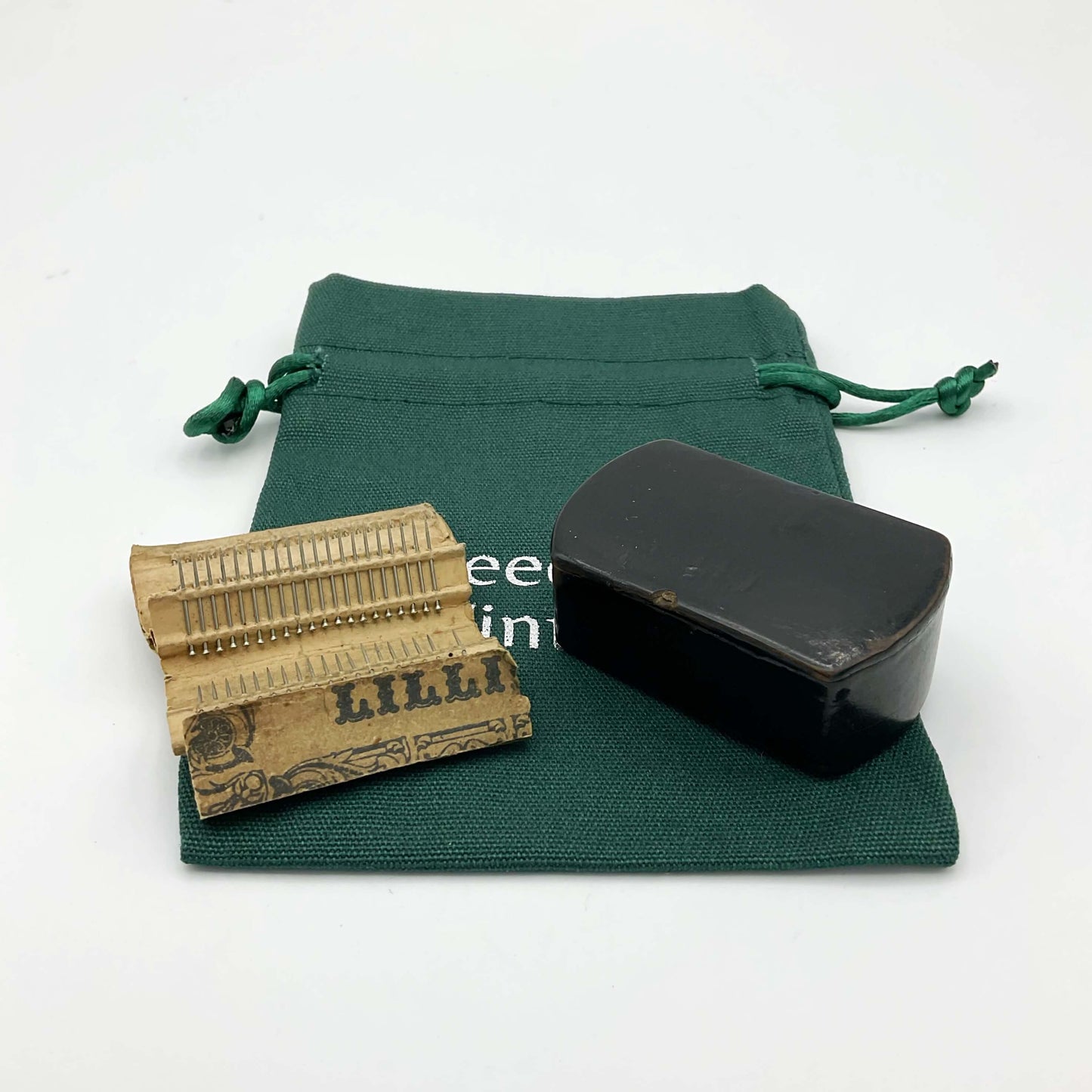 Antique black lacquer snuff box on a green cotton gift bag with Lillikin pins on a paper