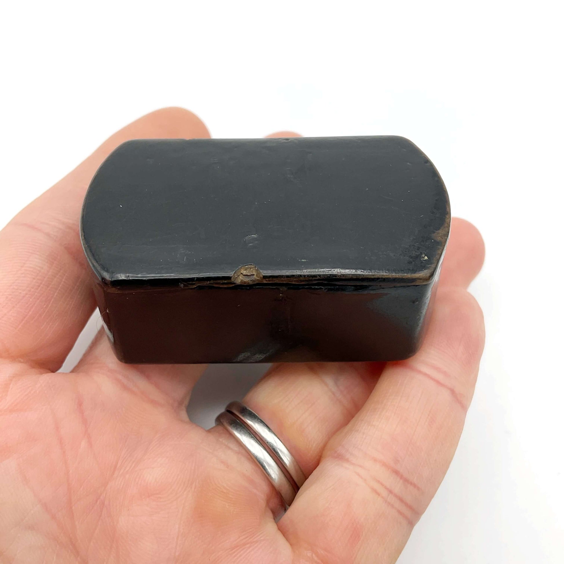 Antique black lacquer snuff box held in a hand