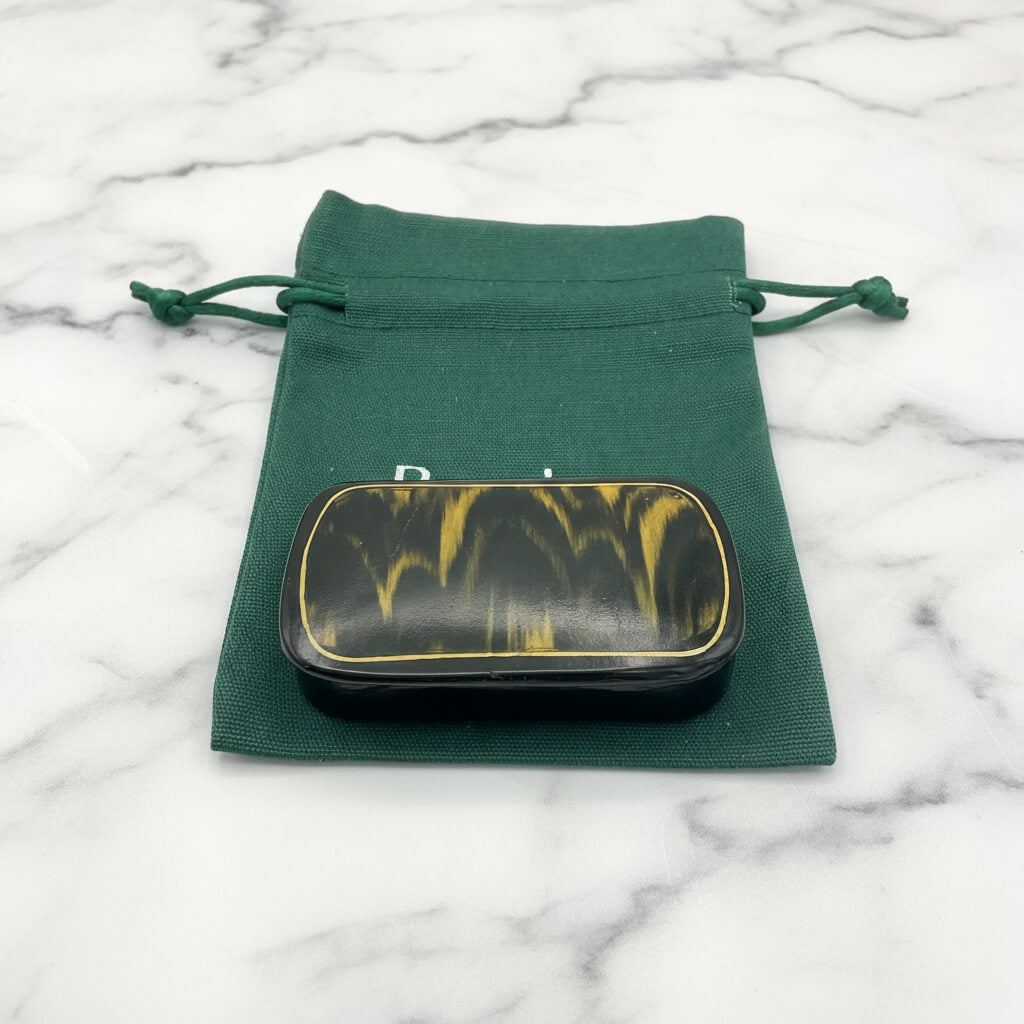 Antique black and gold snuff box on a gift bag and marble worktop