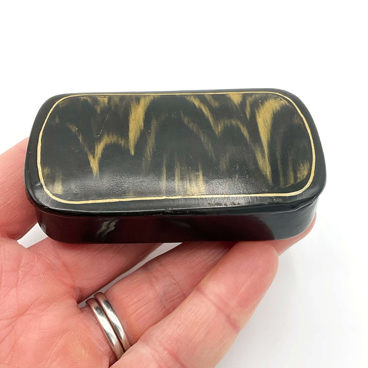 Antique black lacquer and gold snuff box held in a hand