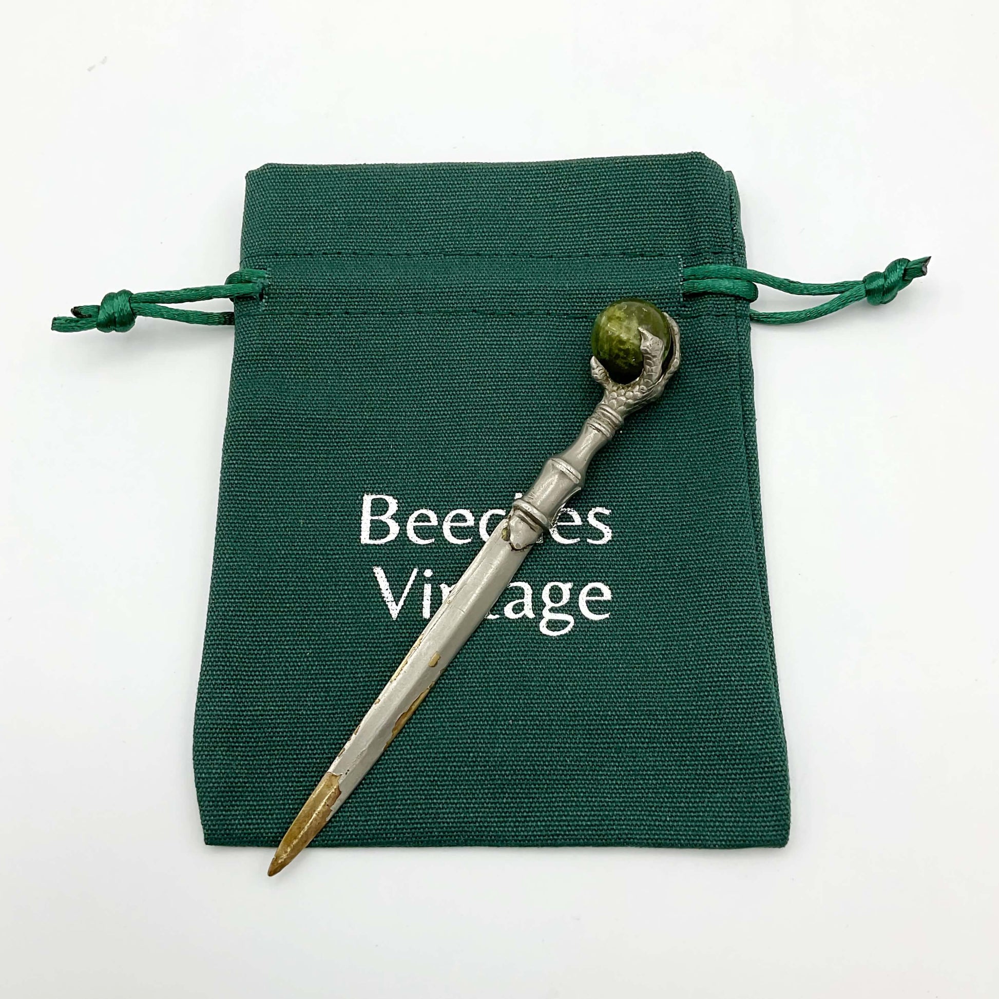 Sword shaped silver plated letter knife on a green gift bag