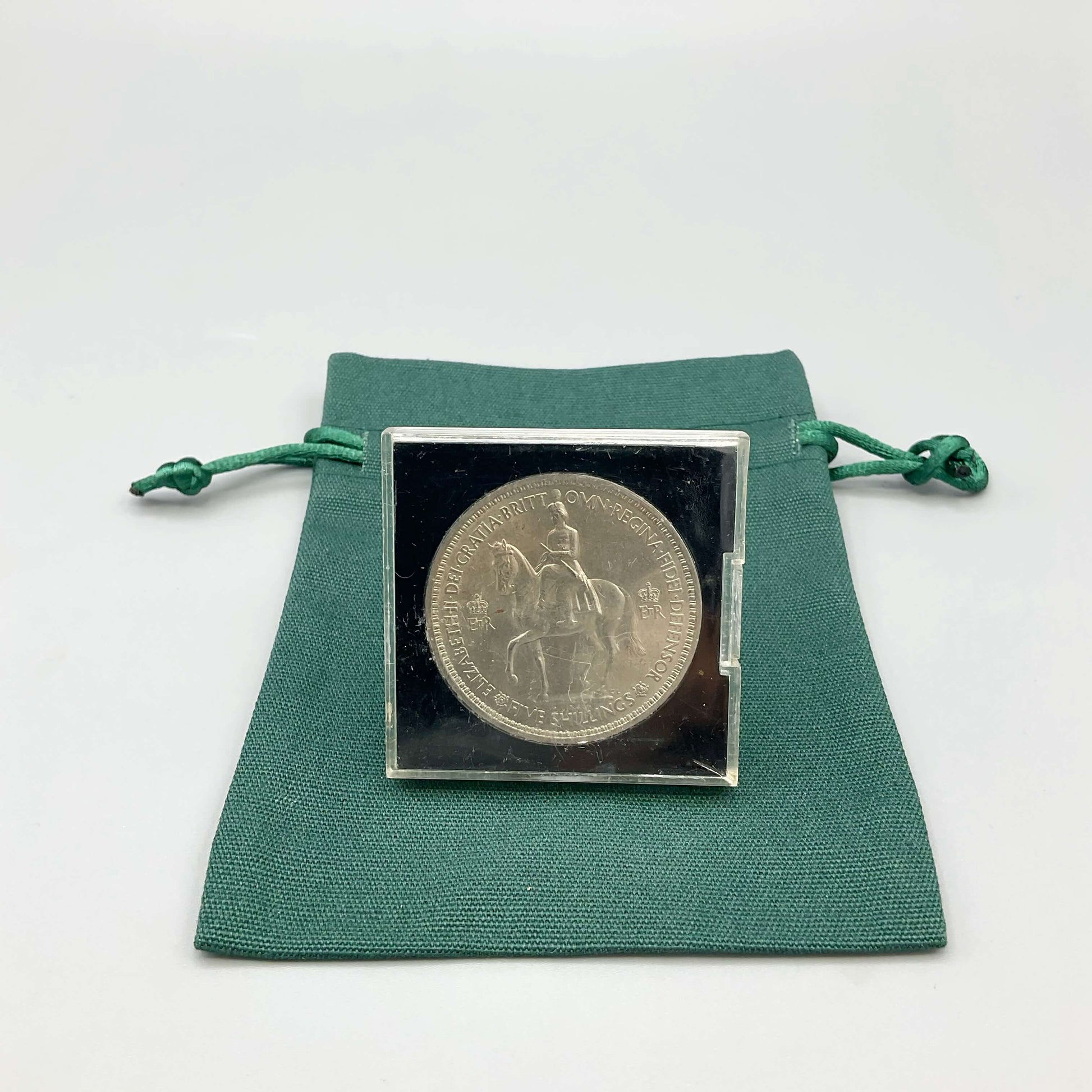 Reverse side of Queen Elizabeth II Coronation Five Shilling Coin in a Perspex Case on a green gift bag